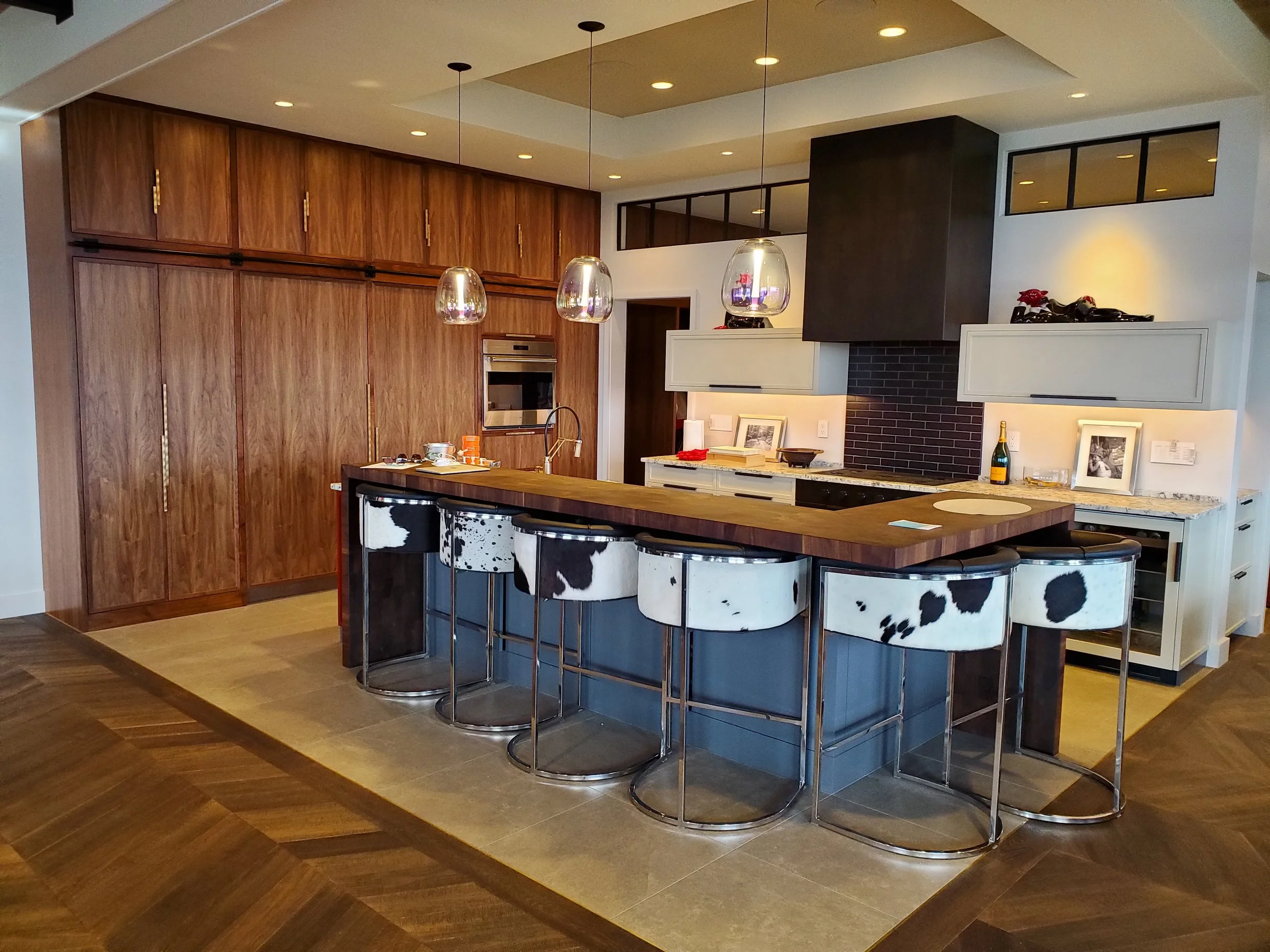 Luxury modern kitchen in Norwich Vermont featuring custom walnut cabinetry, large island with seating, white painted cabinets, and high-end built-in appliances by Hitchcock Woodworking.