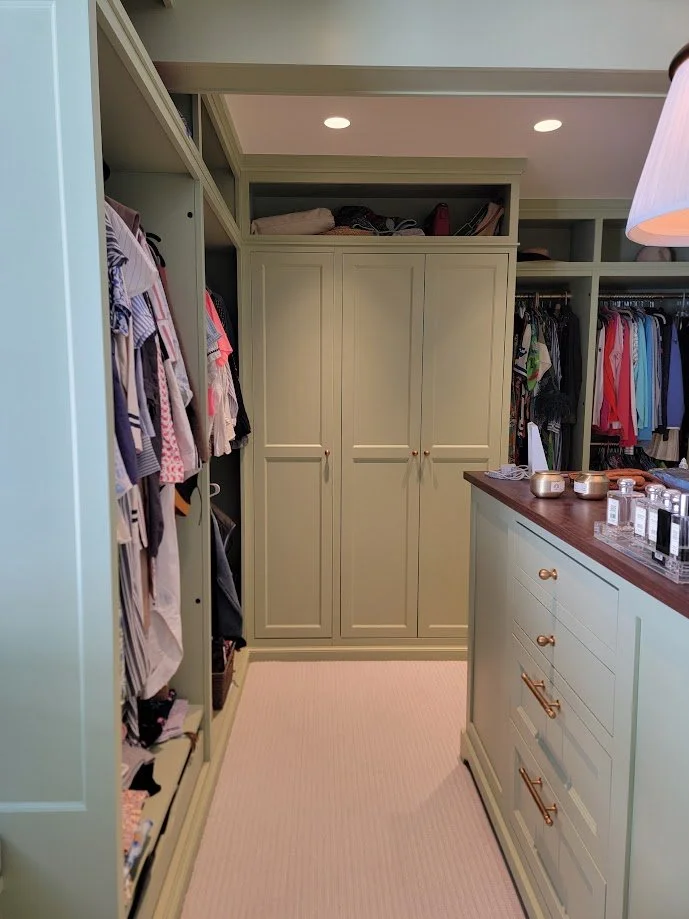 Custom closet island and cabinetry featuring integrated drawers, hanging storage, and refined millwork detailing.