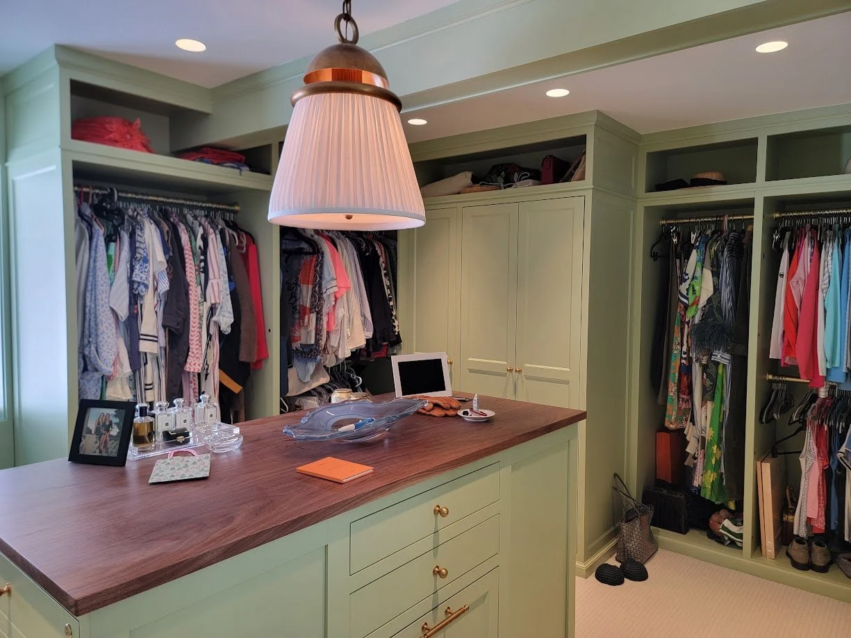 Bold green custom dressing room with center island, built-in cabinetry, and tailored storage solutions.