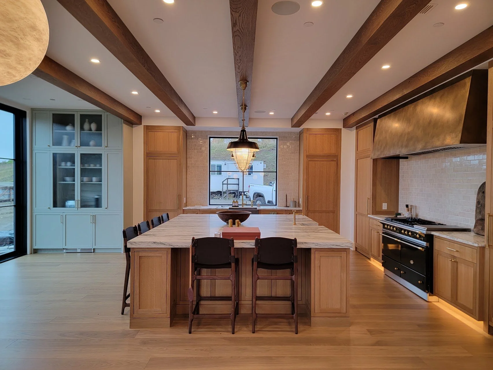 Quartersawn white oak kitchen designed as the central gathering space, with integrated appliances and an expansive island anchoring the layout.