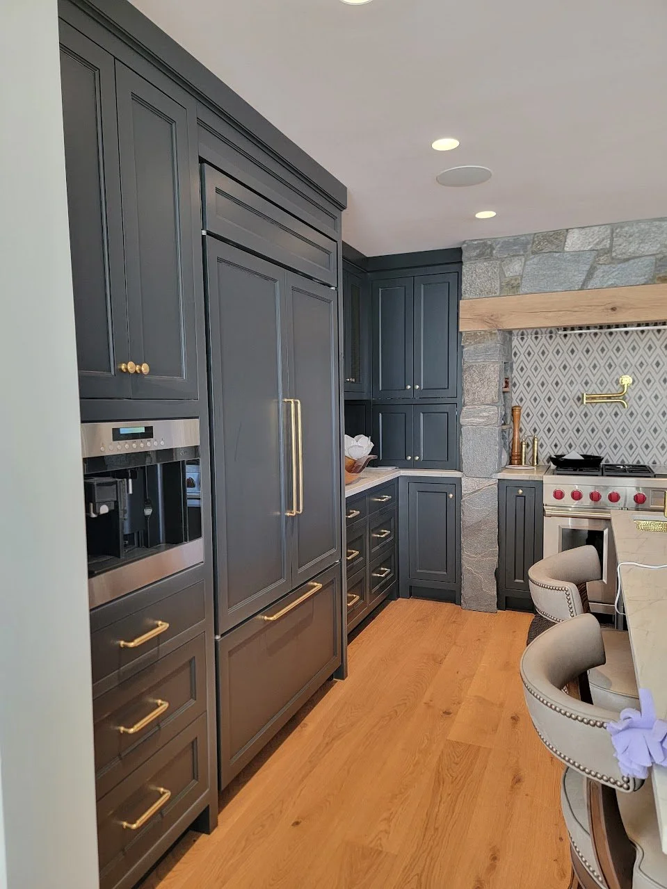 Integrated refrigerator cabinetry within a charcoal black transitional kitchen, showcasing seamless custom millwork.