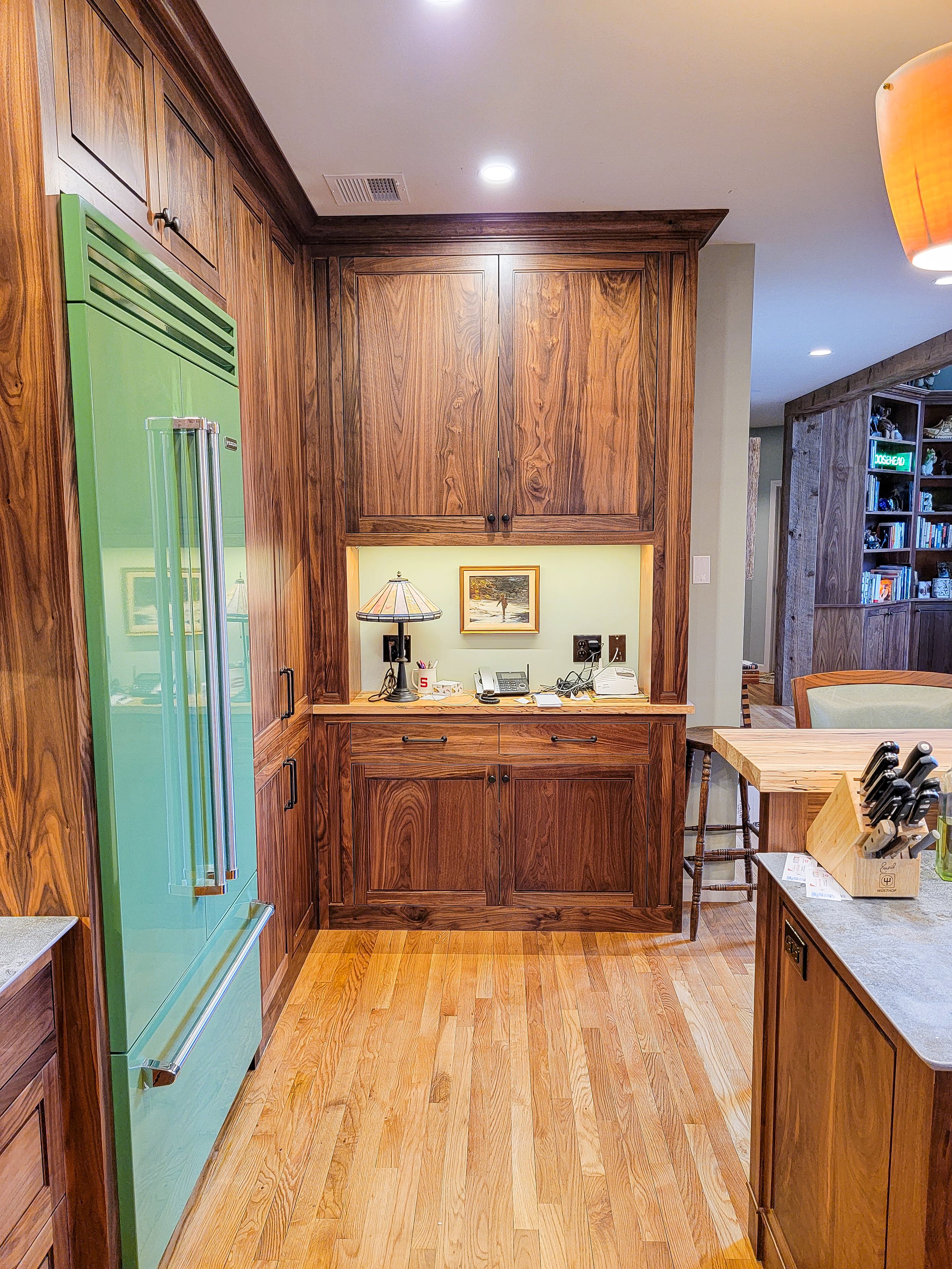 Transitional kitchen featuring custom walnut cabinetry, stone countertops, and integrated appliances in Grantham New Hampshire