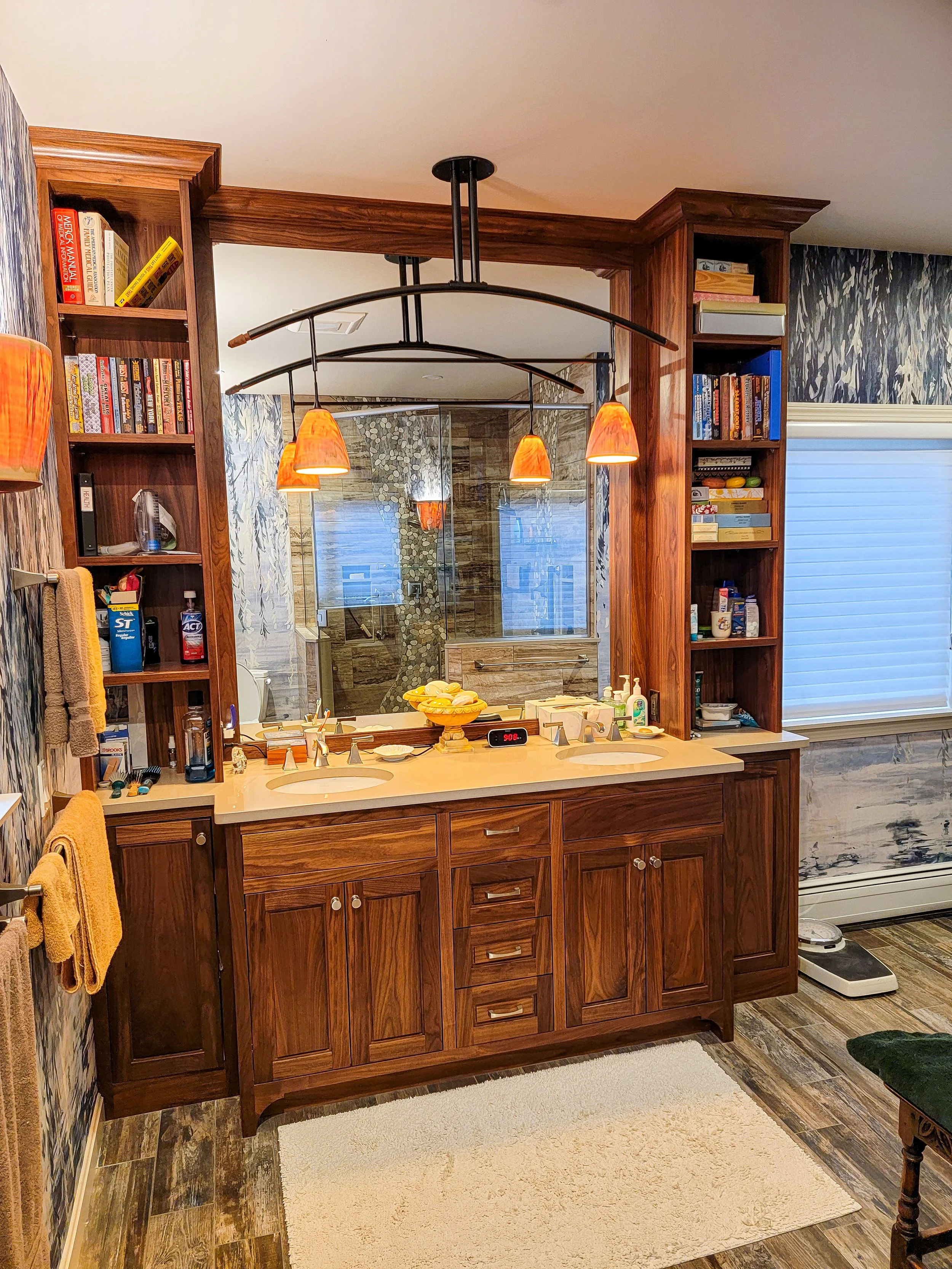 Double sink vanity with custom walnut cabinetry and integrated storage in transitional New Hampshire home
