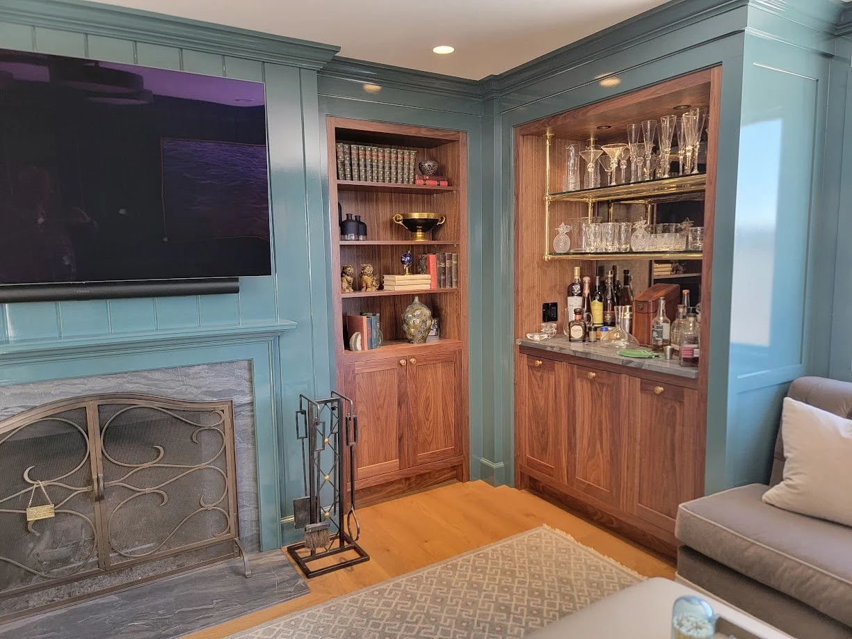 Custom walnut dry bar with high-gloss painted paneling, featuring integrated cabinetry and a warm, refined finish in this Quechee Lakes Vermont golf retreat.