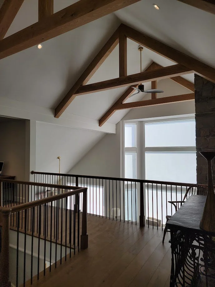 Custom white oak ceiling beams installed in a cathedral great room, adding architectural warmth and structural character.