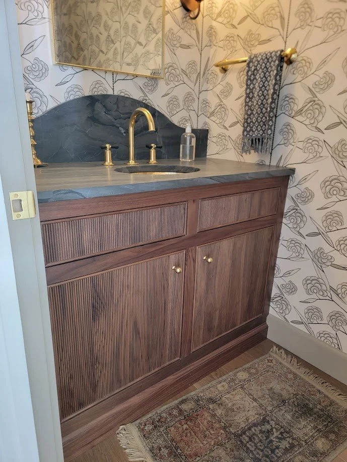 Walnut vanity with reeded door fronts, showcasing detailed craftsmanship and rich natural wood tones.