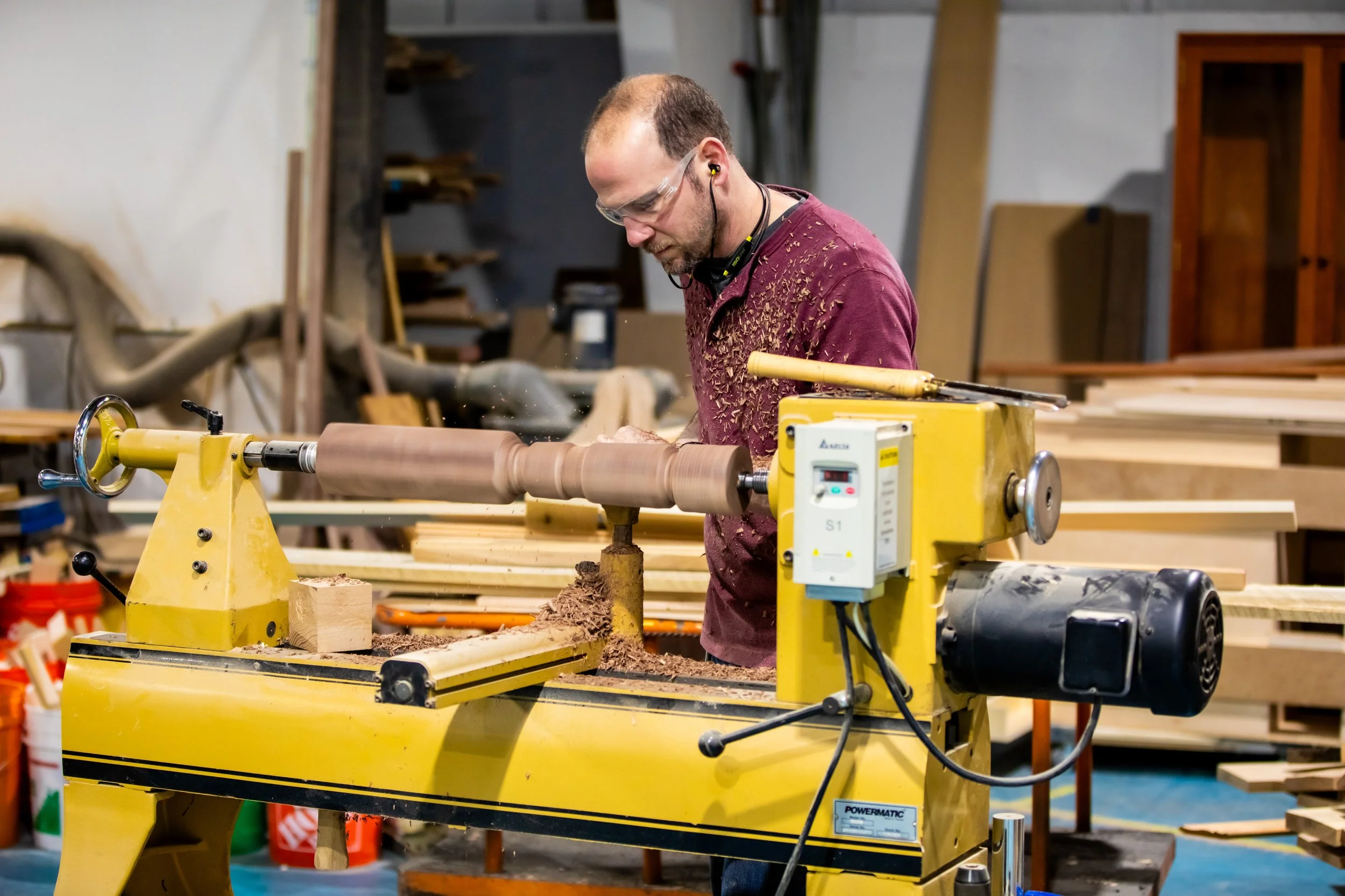 Woodworker shaping a custom table leg using a lathe in the workshop