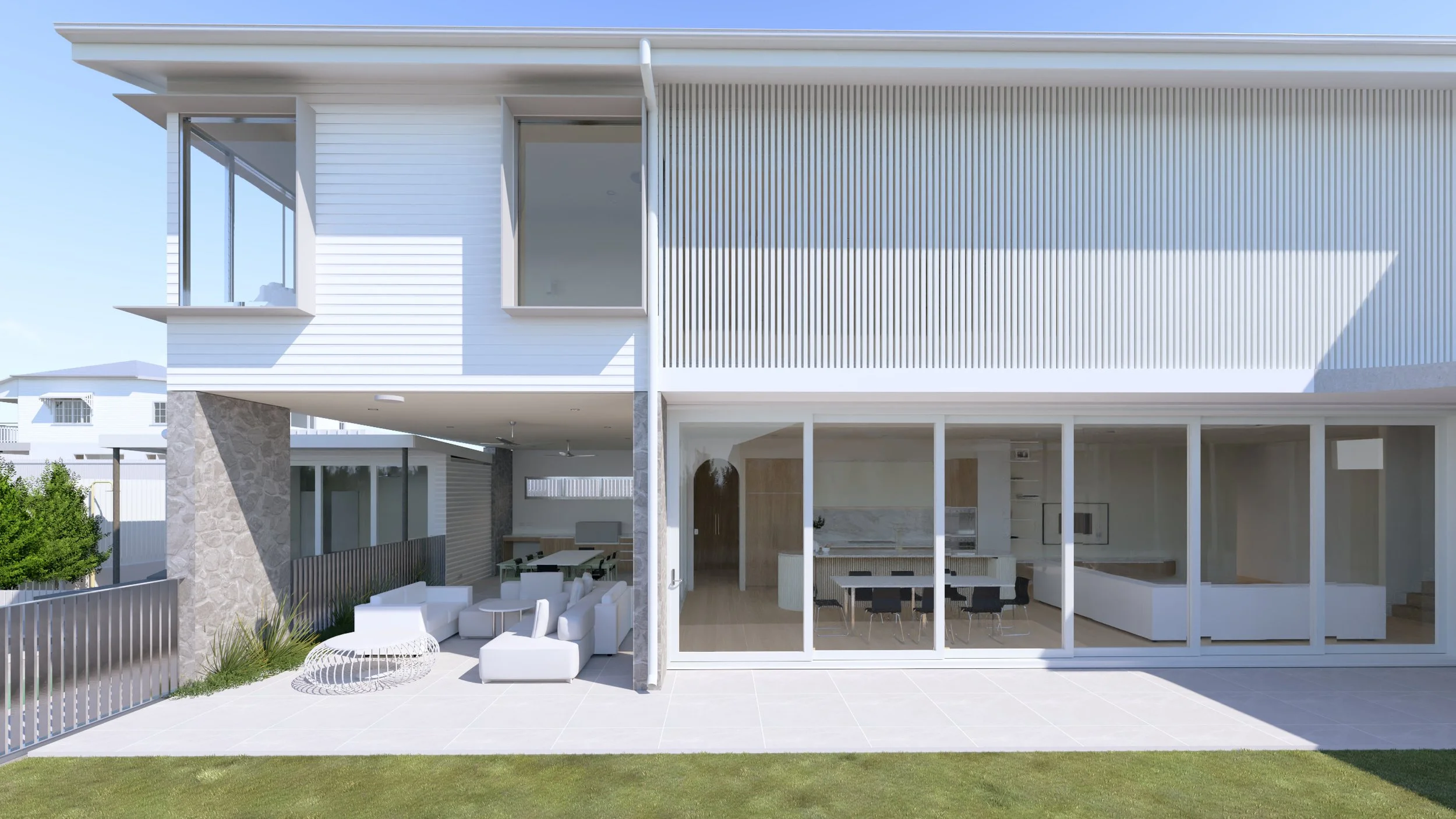 Modern two-story house with large glass doors and patio, white exterior, outdoor seating area, and landscaped yard.