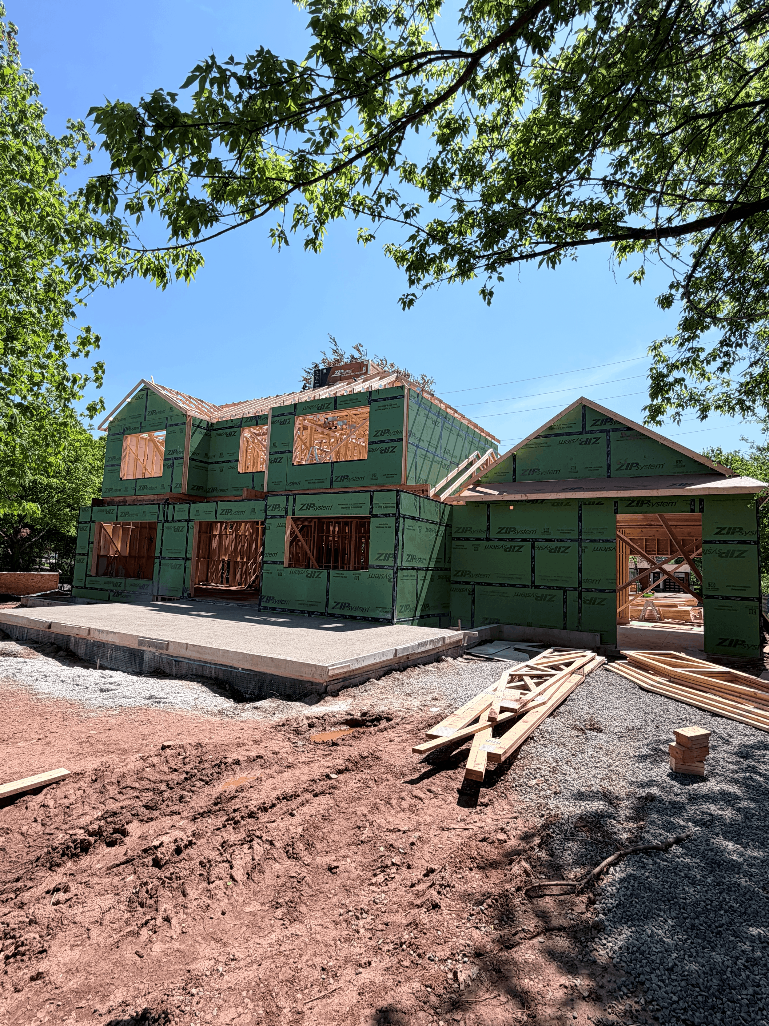 P1A Project. A house under construction with framing and sheathing, surrounded by trees and a clear blue sky.