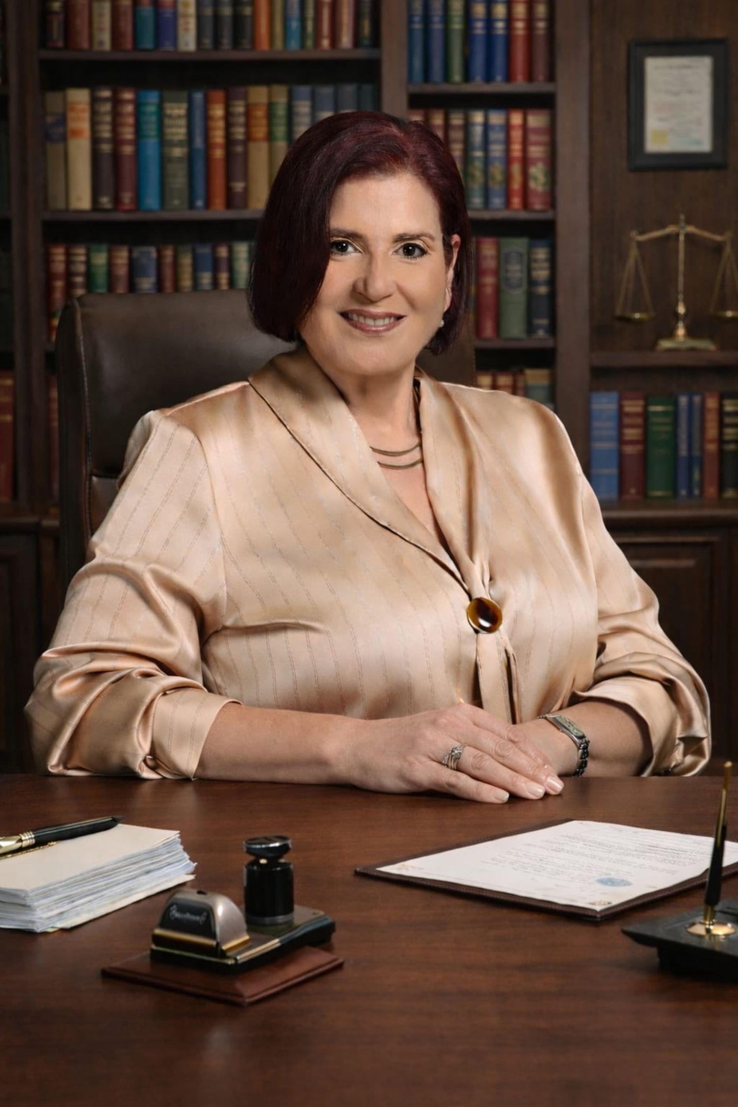 Lcda. Almarie Ferrer en su oficina rodeada de libros jurídicos, representando experiencia en servicios notariales, sucesiones y trámites legales.