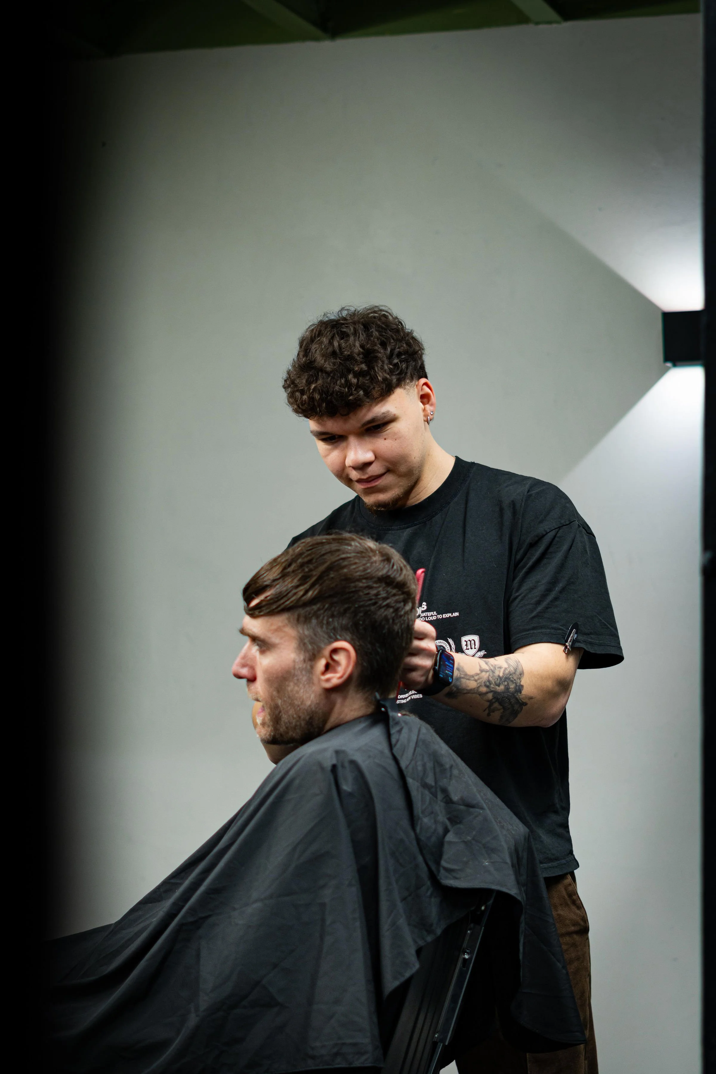 A barber cuts a male customer's hair in a salon.