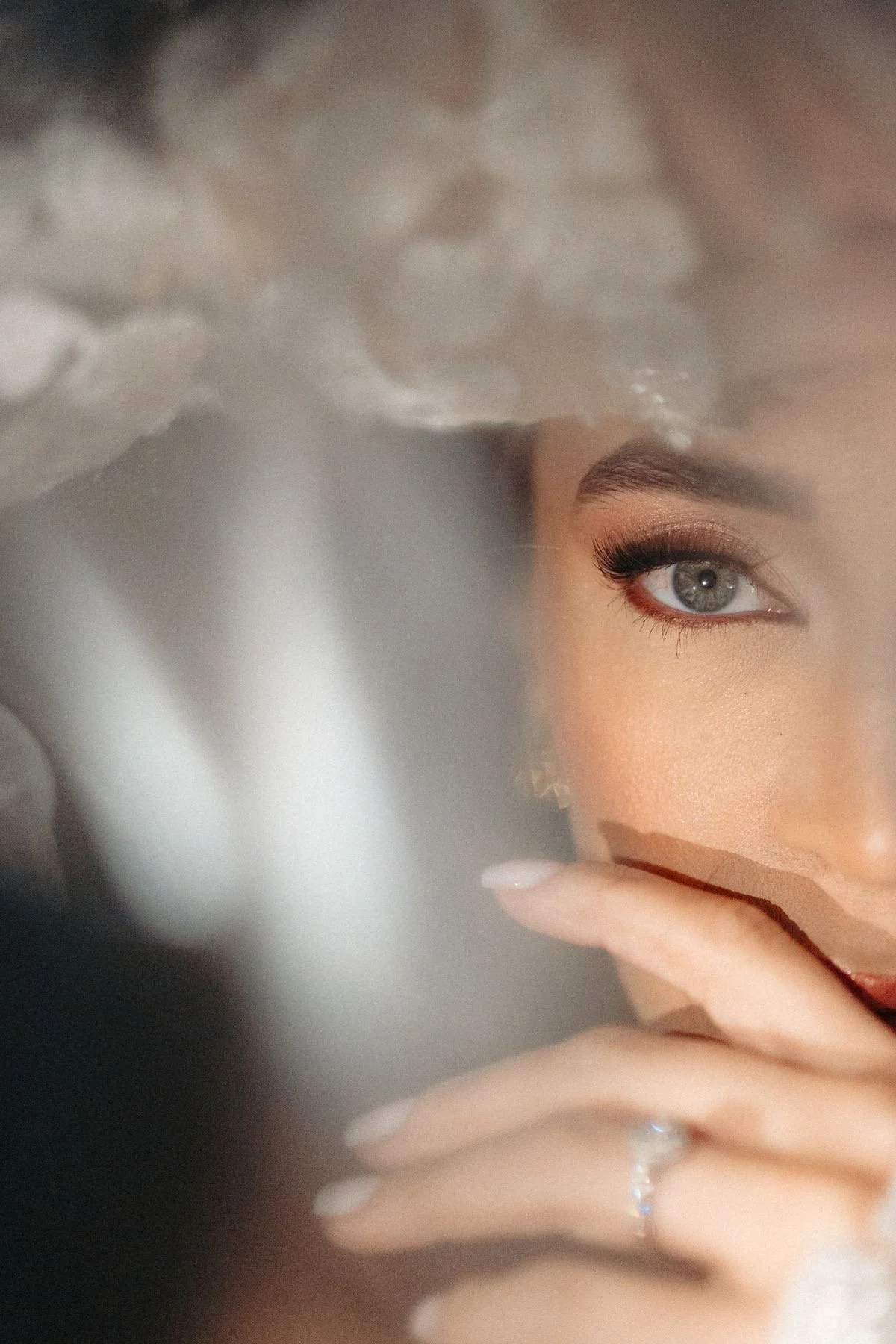 Close-up of a woman's face, focusing on her eye, with her finger near her lips. Soft lighting highlights her makeup and eye color.