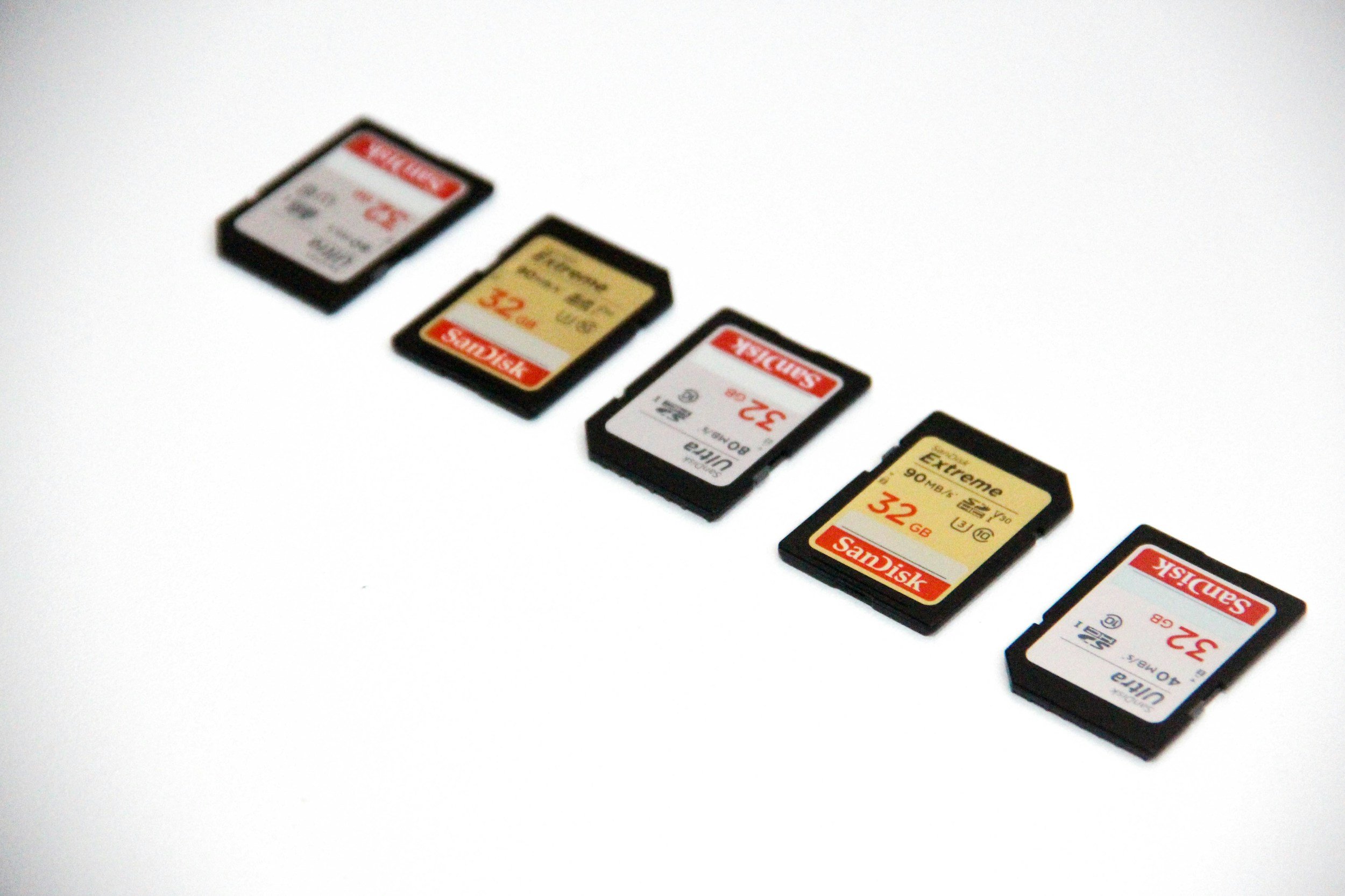 Six SD memory cards lined up in a row on a white surface.