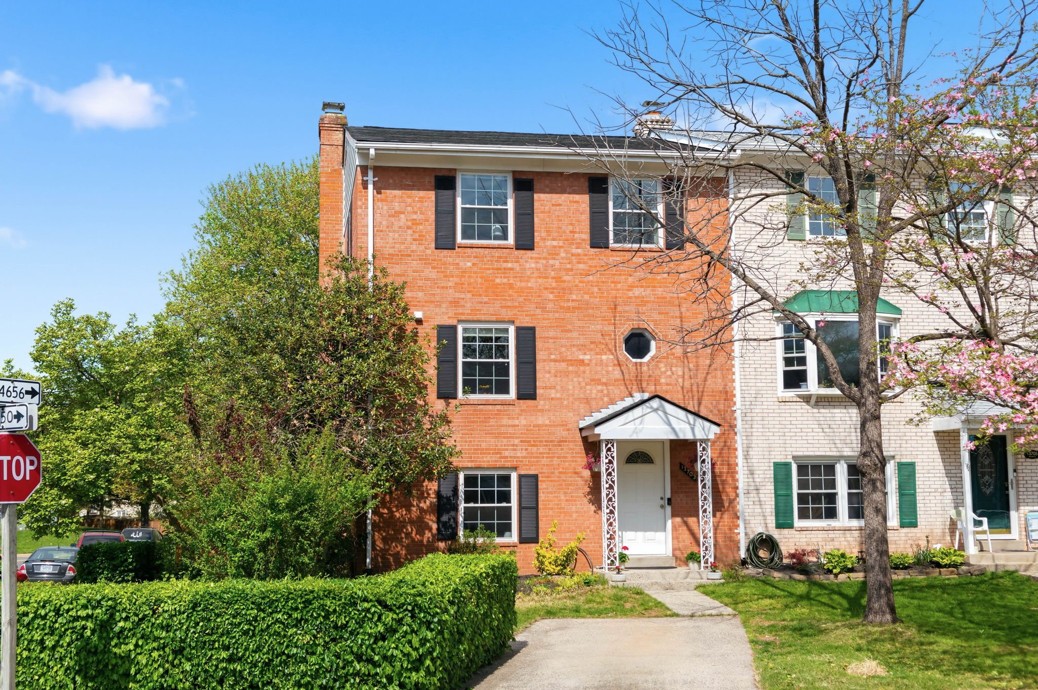 Exterior view of a 4-bedroom brick end-unit townhouse for sale at 13703 Penwith Ct in Chantilly, VA featuring a large fenced yard.