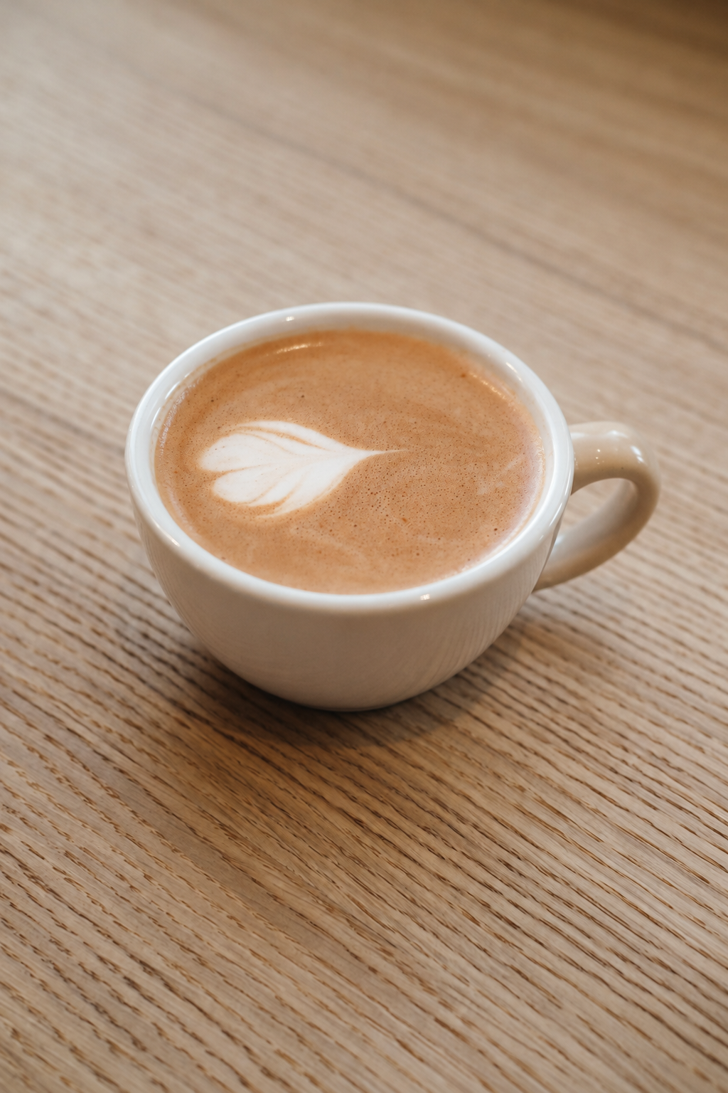 Café latte artistique sur table en bois.png