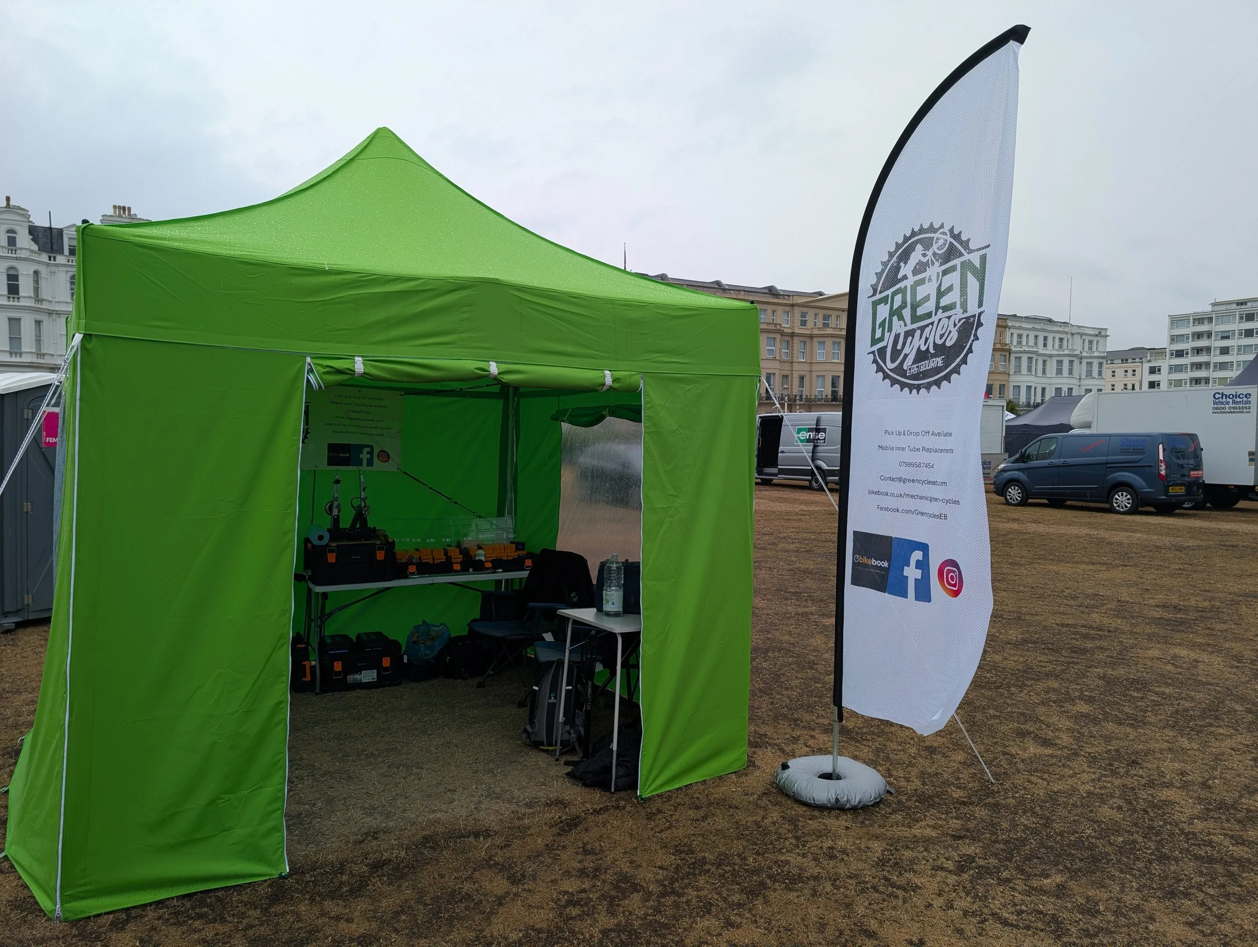 Green outdoor tent with a flag displaying 'Green Cycles' and social media icons.