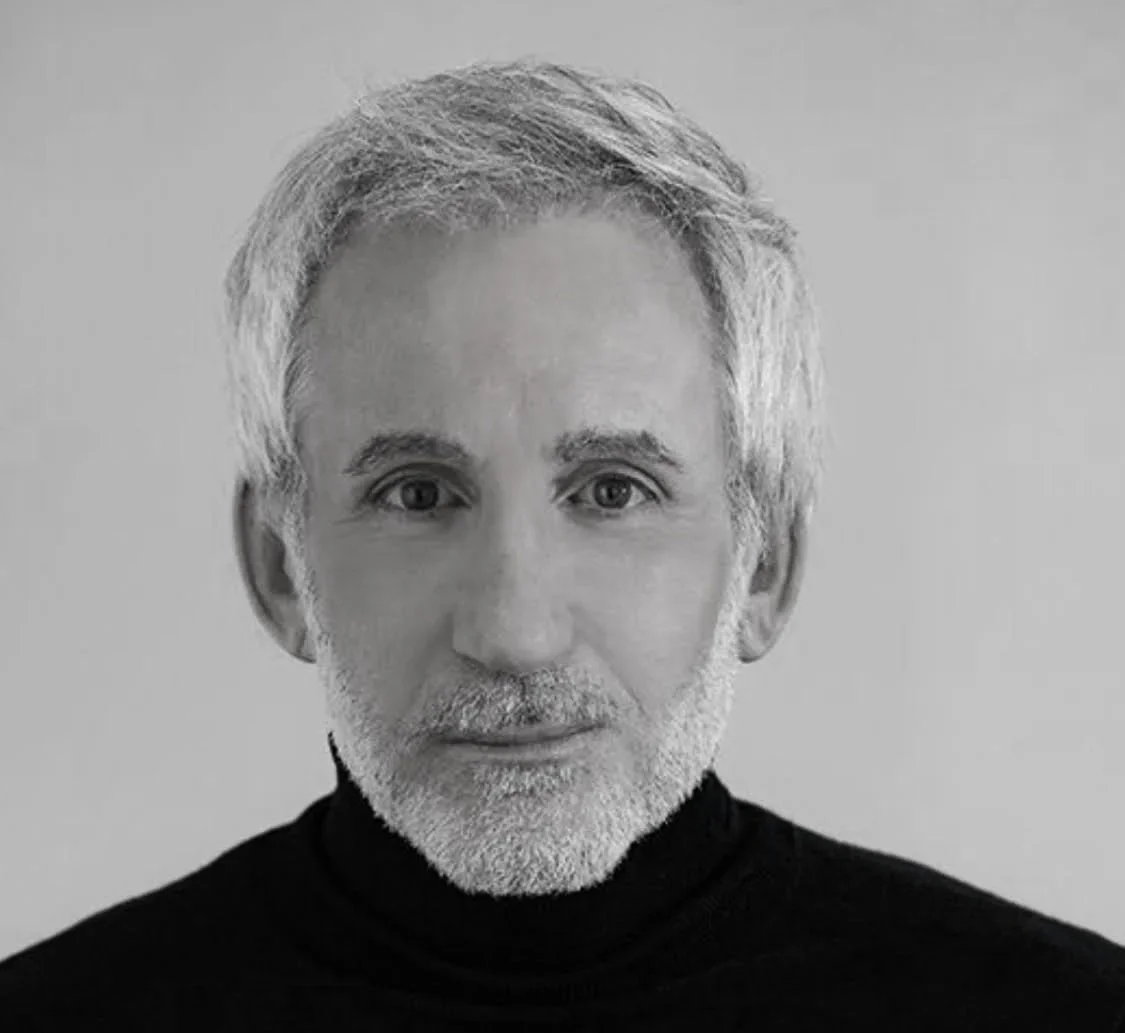 Black and white portrait of an older man with short gray hair, a beard, and wearing a black turtleneck.