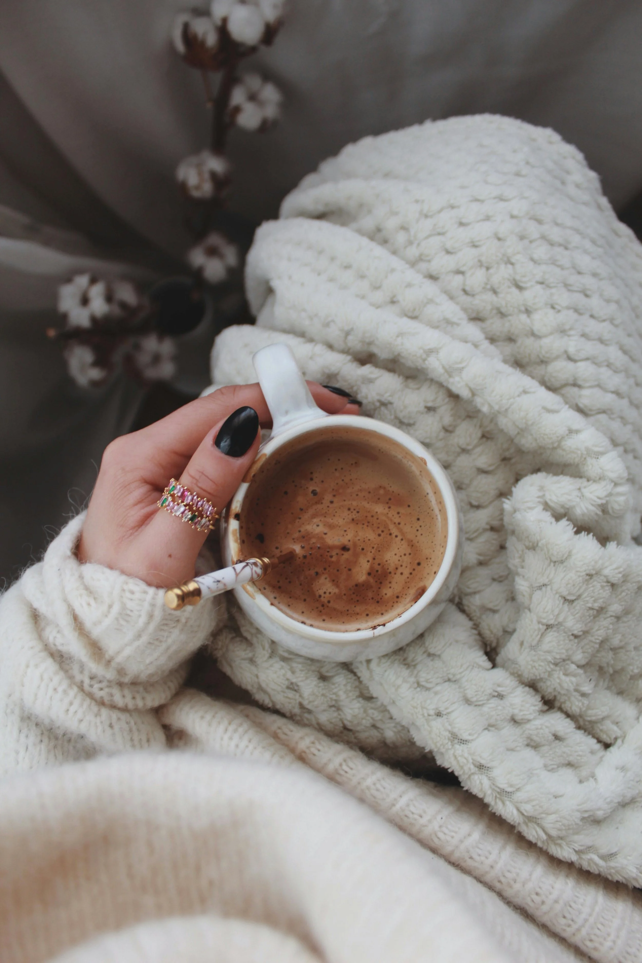 hand holding drink on lap with cozy blanket