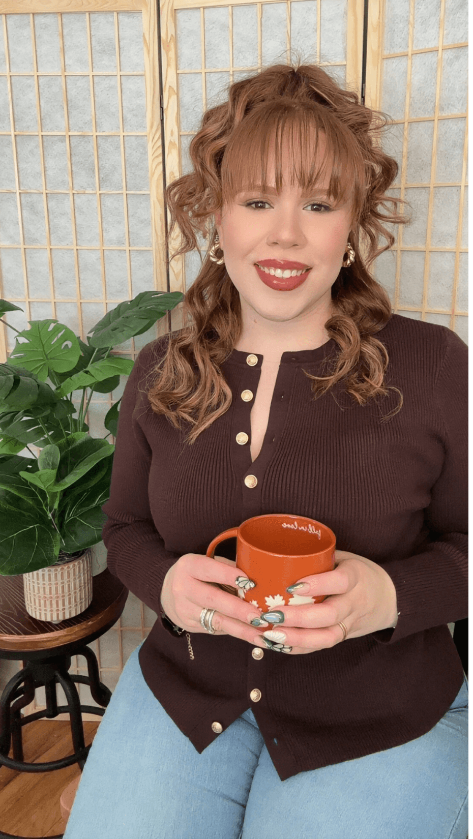 Felishatee Rodriguez in her therapy office holding an orange mug.