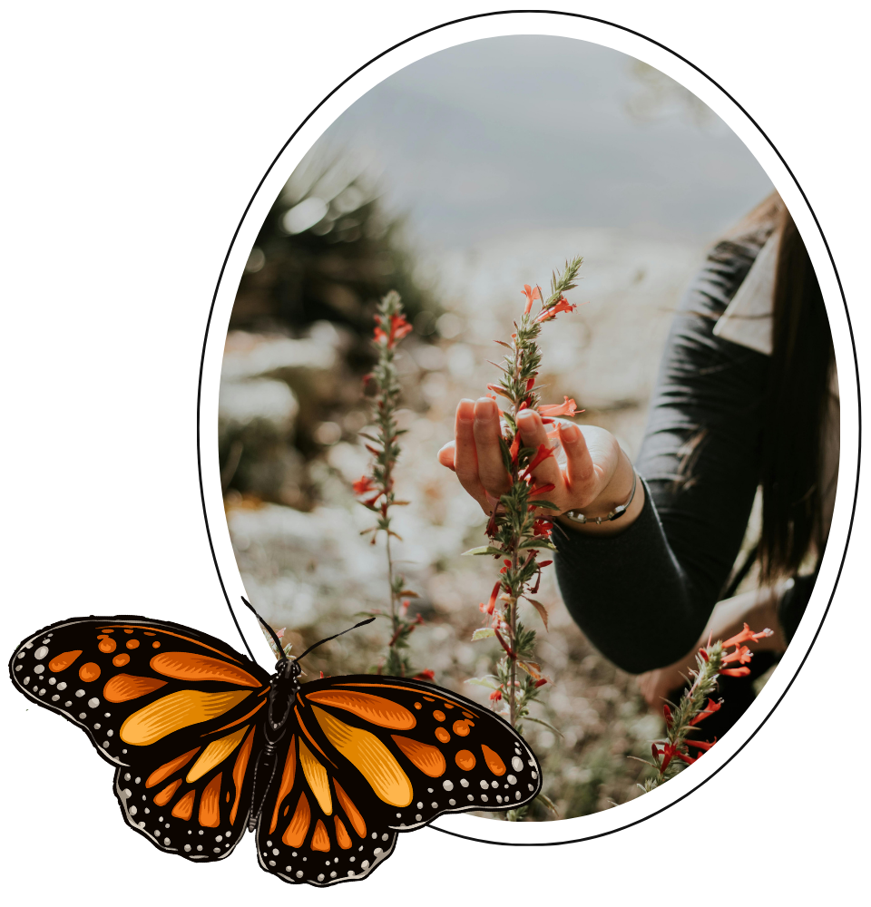 A person in a jacket touching a pink flower on a tall stem outdoors.