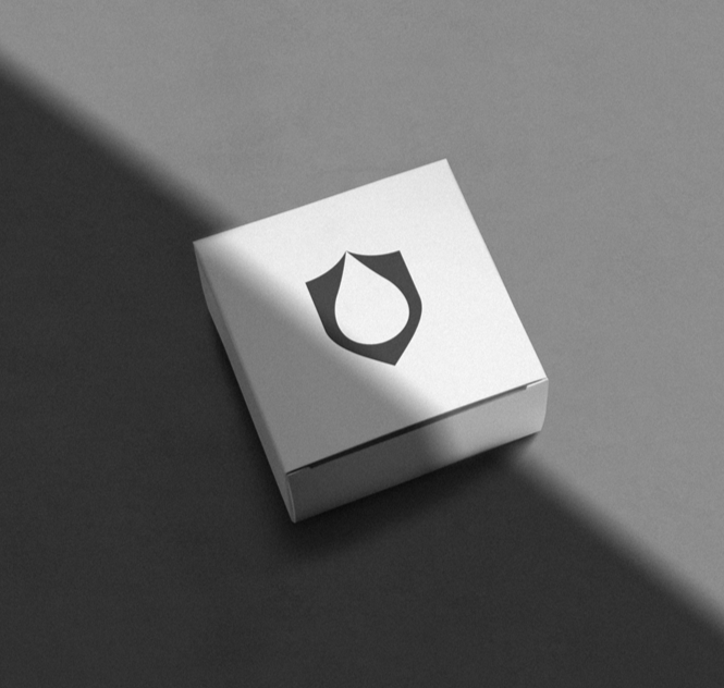 A small white box with a shield logo on the top, placed on a surface with a shadow cast to the left.