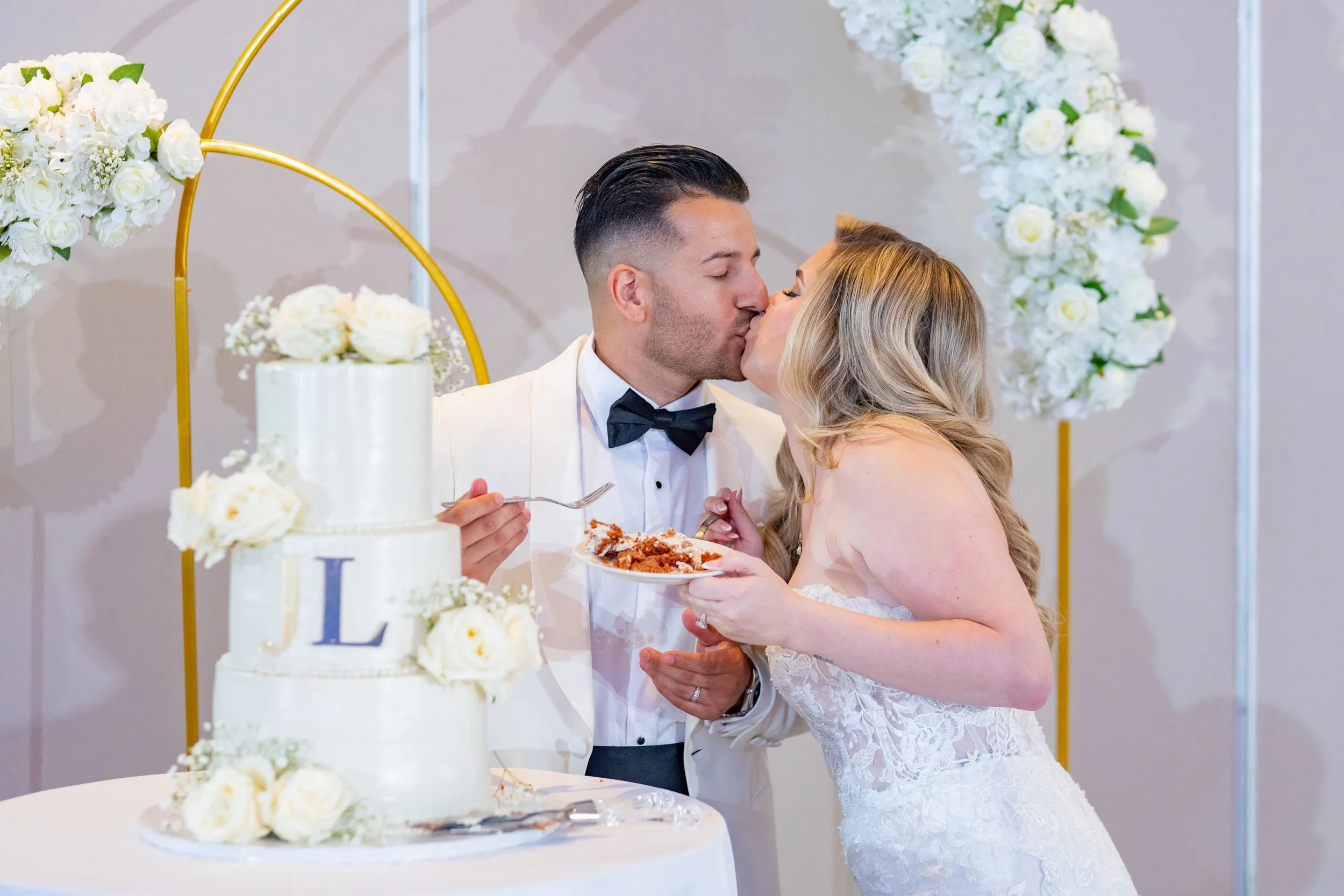Newlyweds sharing a romantic kiss while cutting their wedding cake at HILTON TAMPA DOWNTOWN; luxury reception details and photography by Star Visual Art, Tampa.