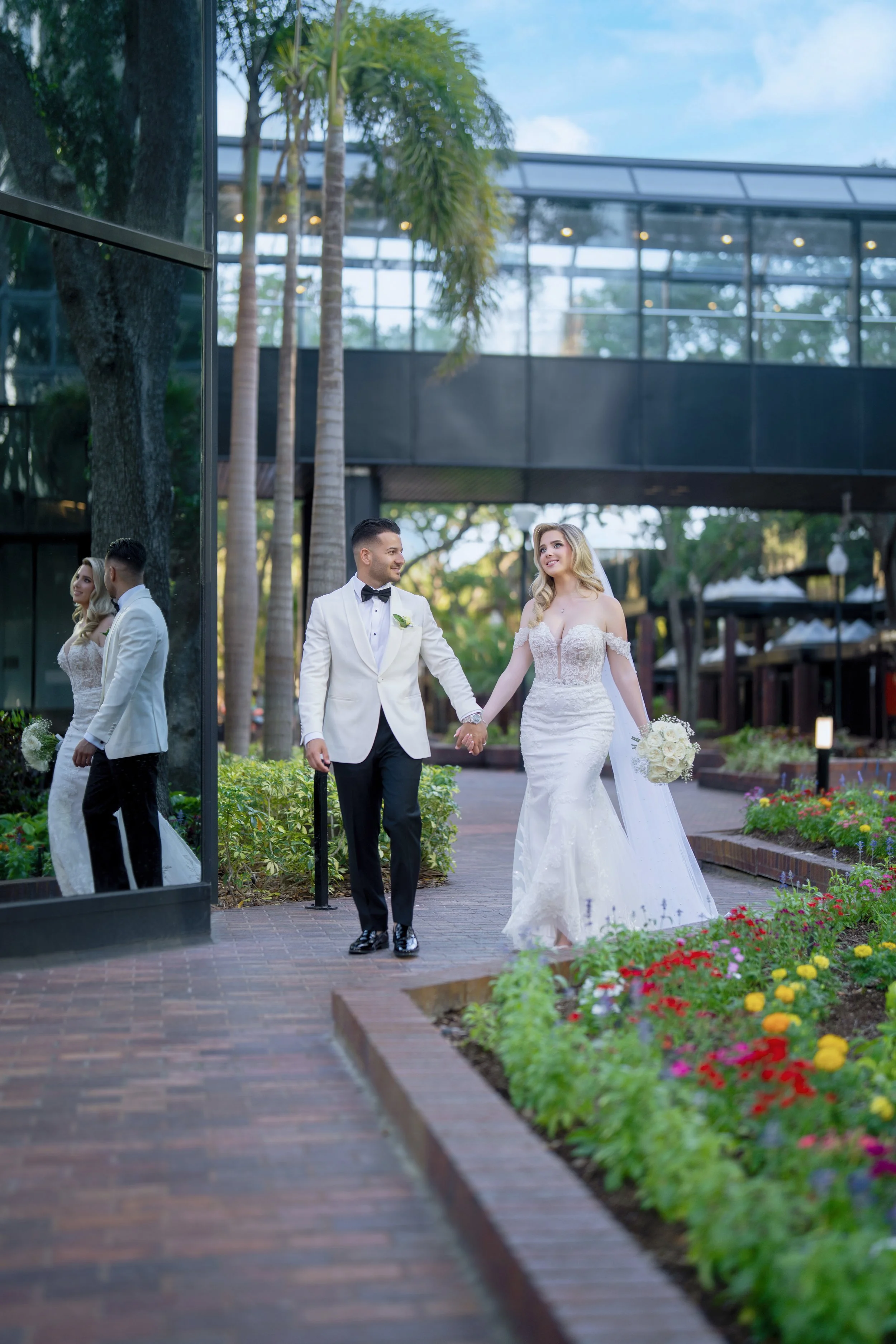 Newlyweds walking together through the lush gardens at HILTON TAMPA DOWNTOWN; romantic outdoor wedding photography by Star Visual Art, Tampa.