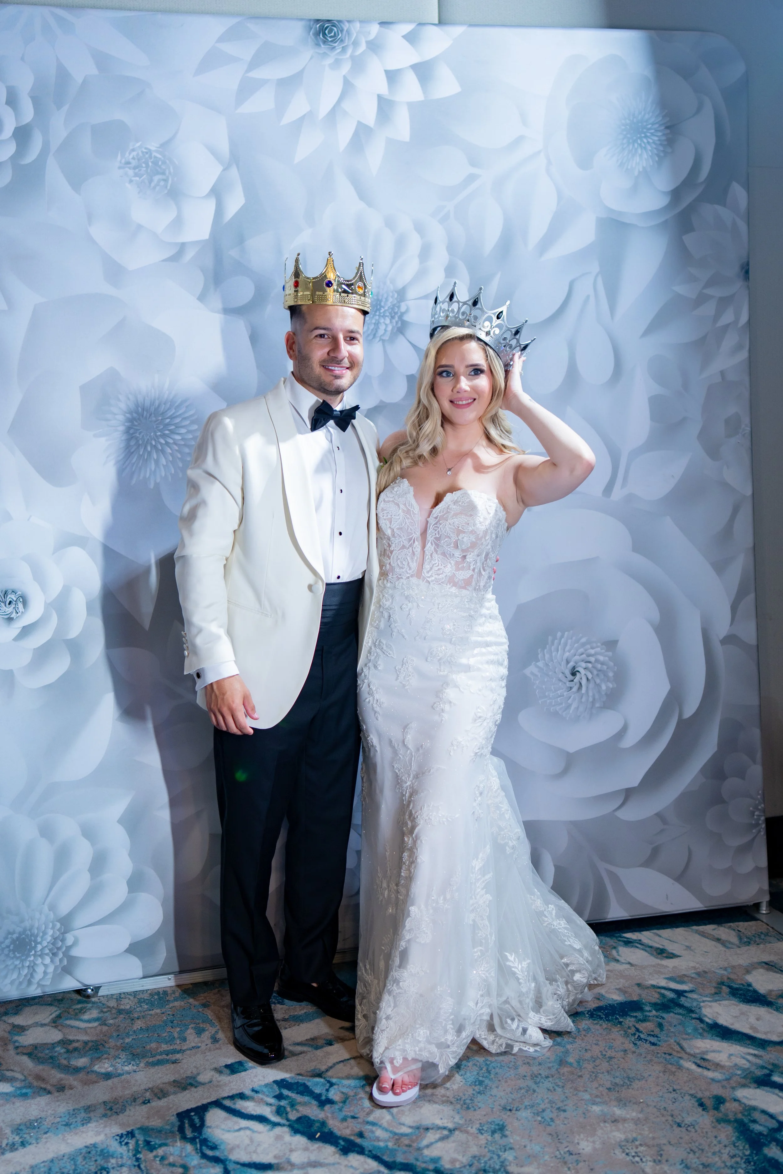 Stylish newlyweds posing with party crowns against a blue backdrop at HILTON TAMPA DOWNTOWN; editorial wedding reception photography by Star Visual Art, Tampa.