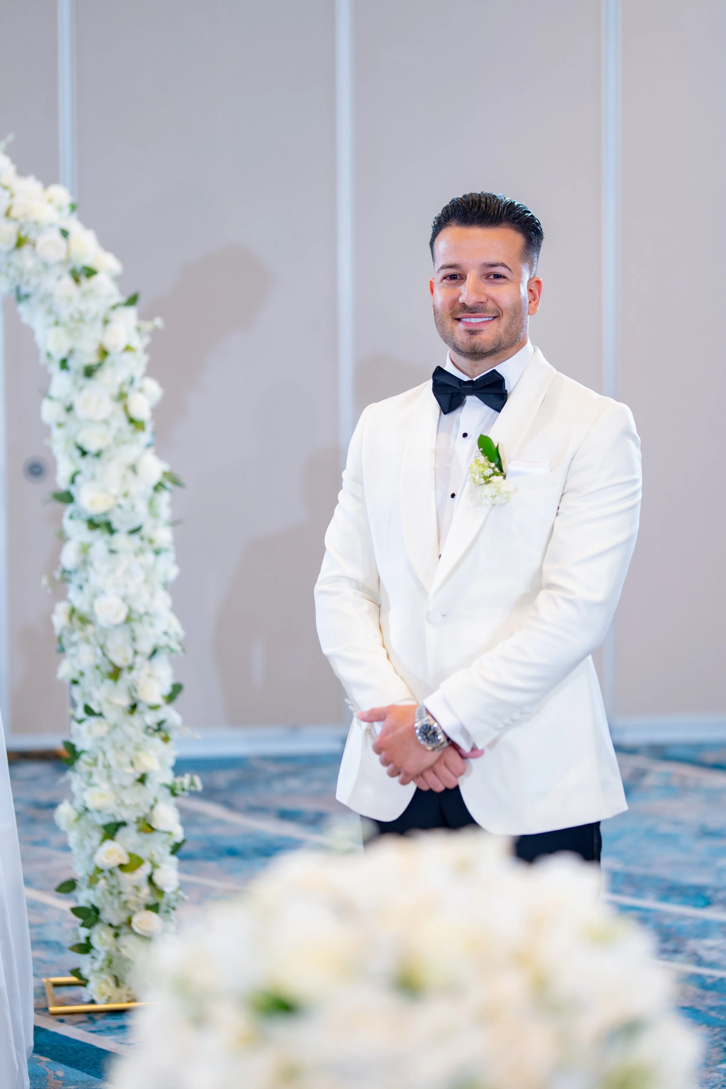 Groom's grand entrance in a white tuxedo at HILTON TAMPA DOWNTOWN; professional wedding ceremony photography by Star Visual Art, Tampa.