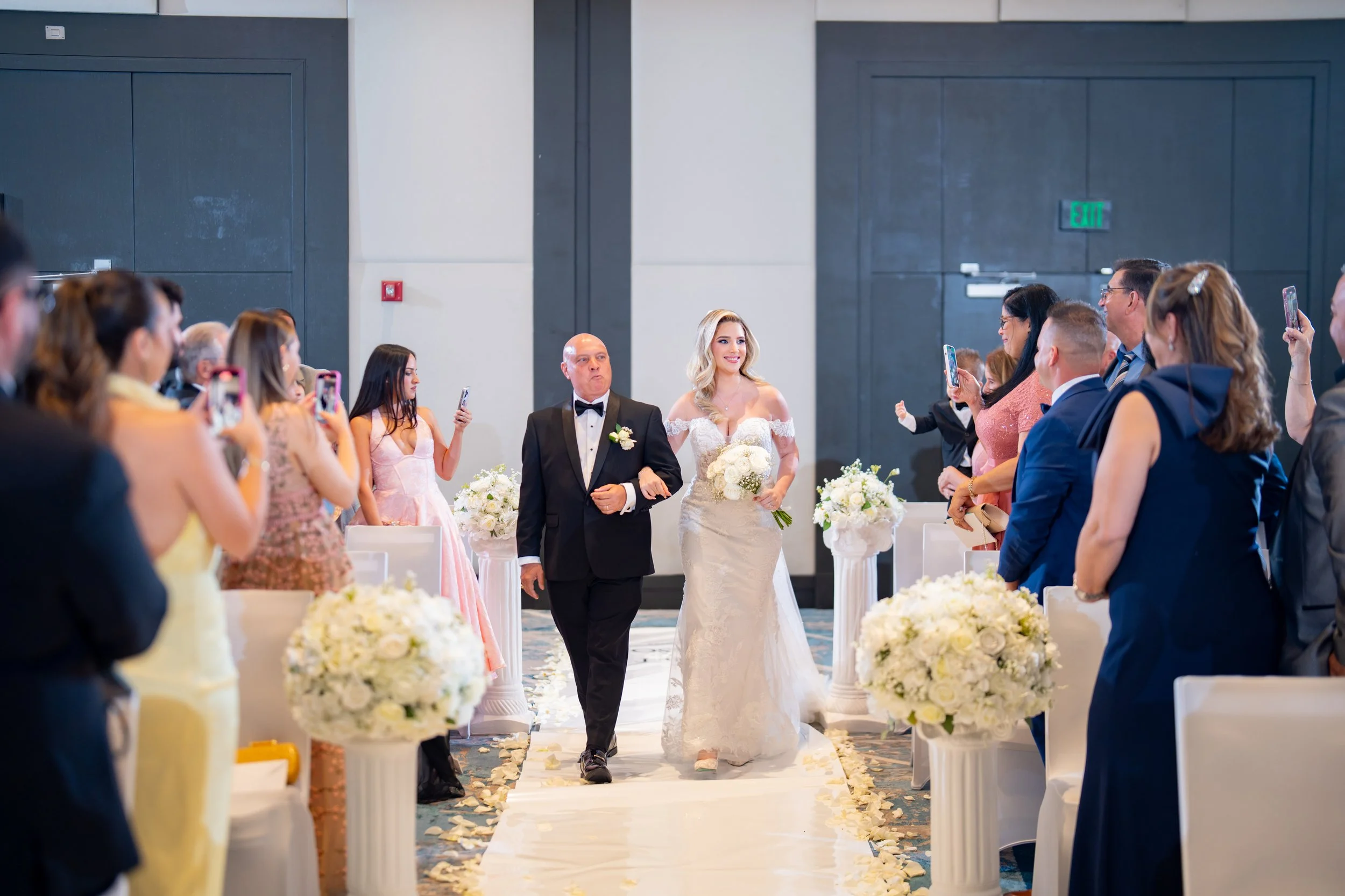 Groom's grand entrance in a white tuxedo at HILTON TAMPA DOWNTOWN; professional wedding ceremony photography by Star Visual Art, Tampa.