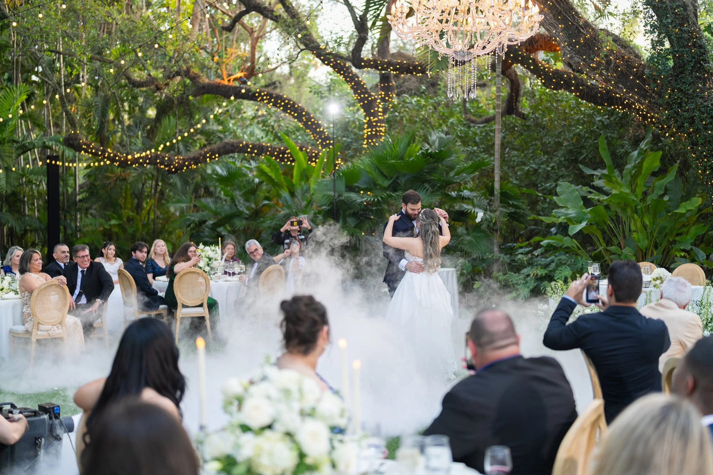 Romantic first dance with a "dancing on the clouds" smoke effect under the Banyan tree at Villa Woodbine; luxury wedding photography by Star Visual Art, Miami.