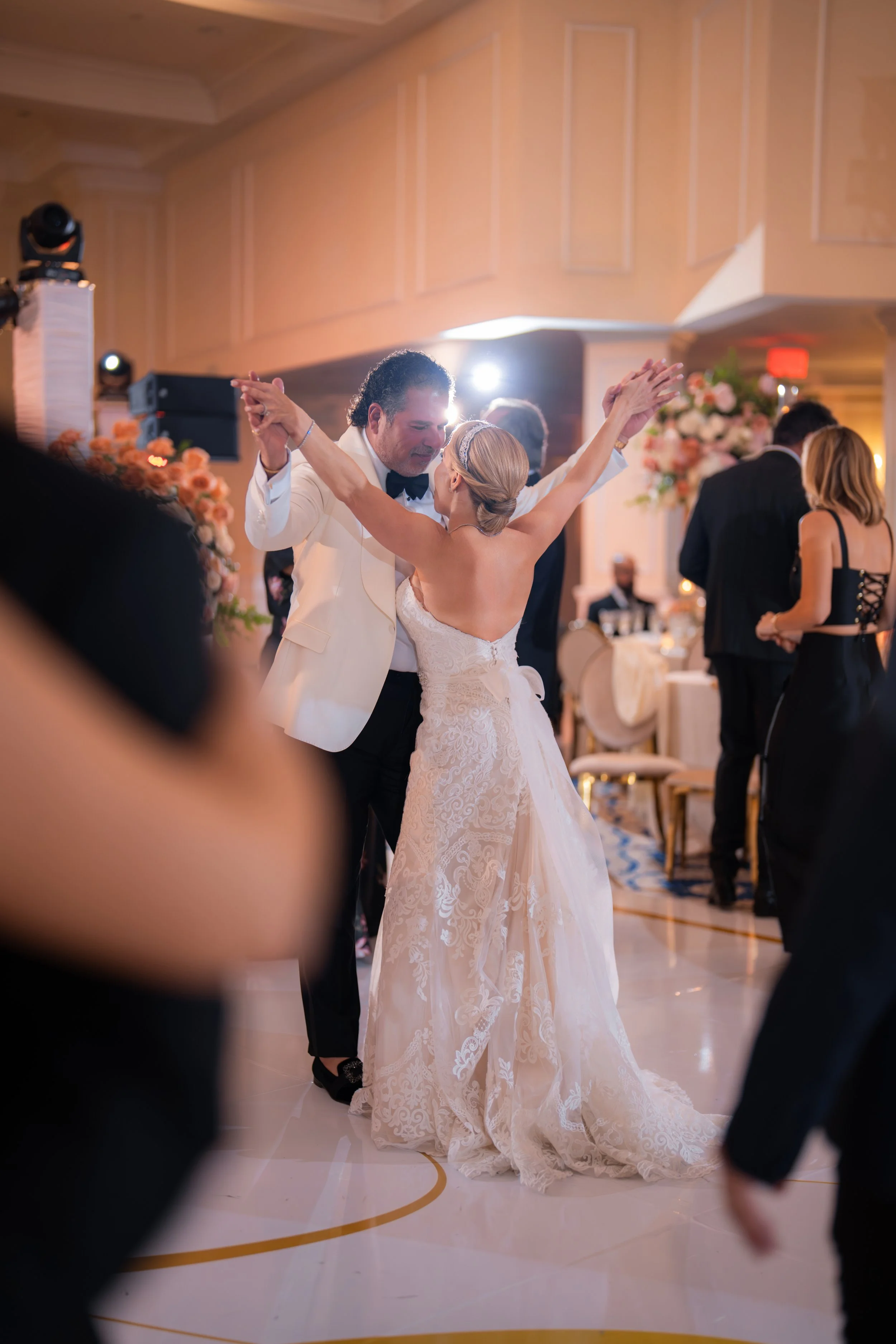A bride and groom dancing at their wedding reception inside a decorated banquet hall.