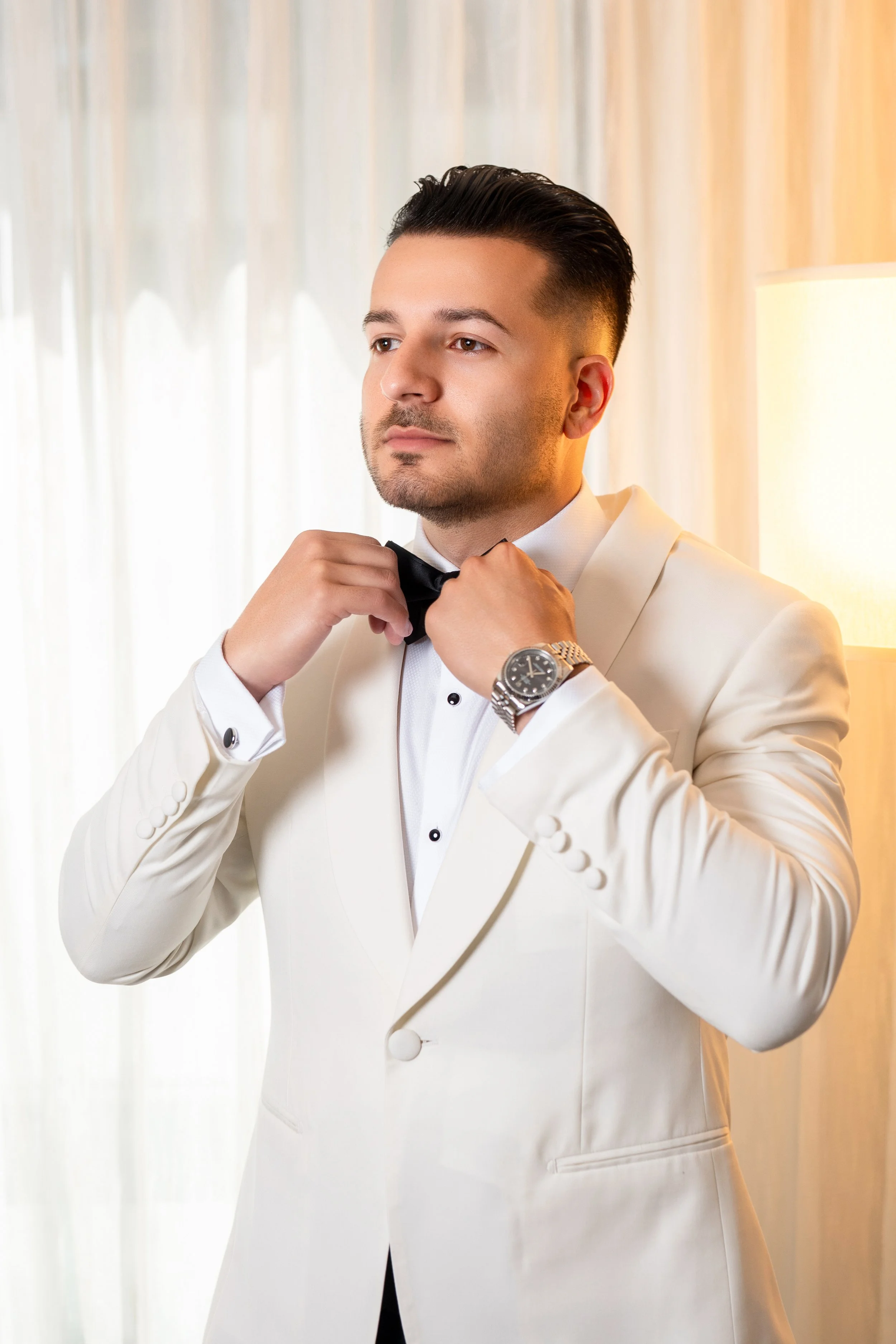 Sophisticated groom portrait in a white tuxedo during the getting ready session at HILTON TAMPA DOWNTOWN; fine art photography by Star Visual Art, Tampa.