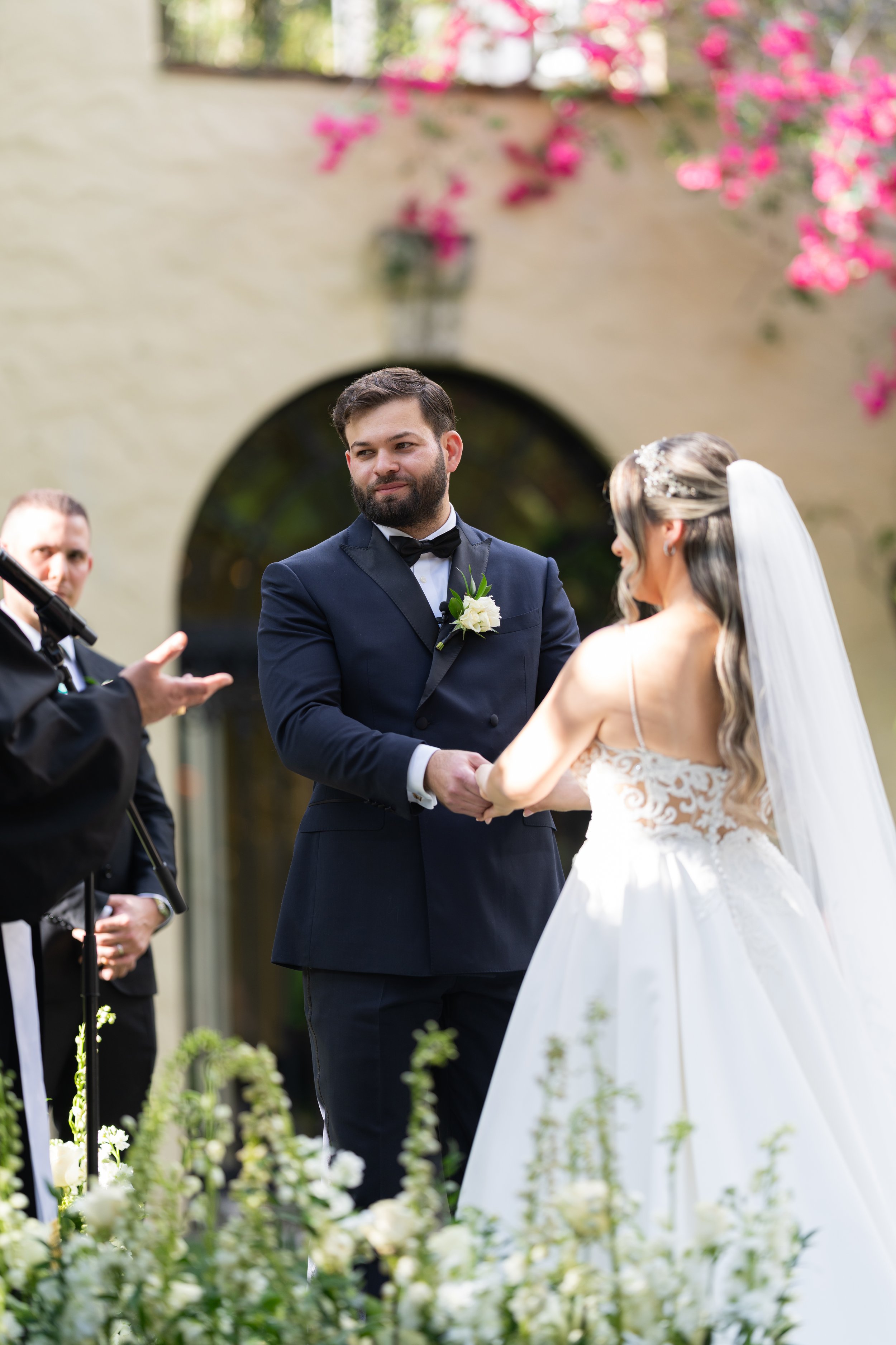 Romantic couple portrait during an outdoor wedding ceremony at Villa Woodbine with pink bougainvillea; fine art photography by Star Visual Art, Miami.