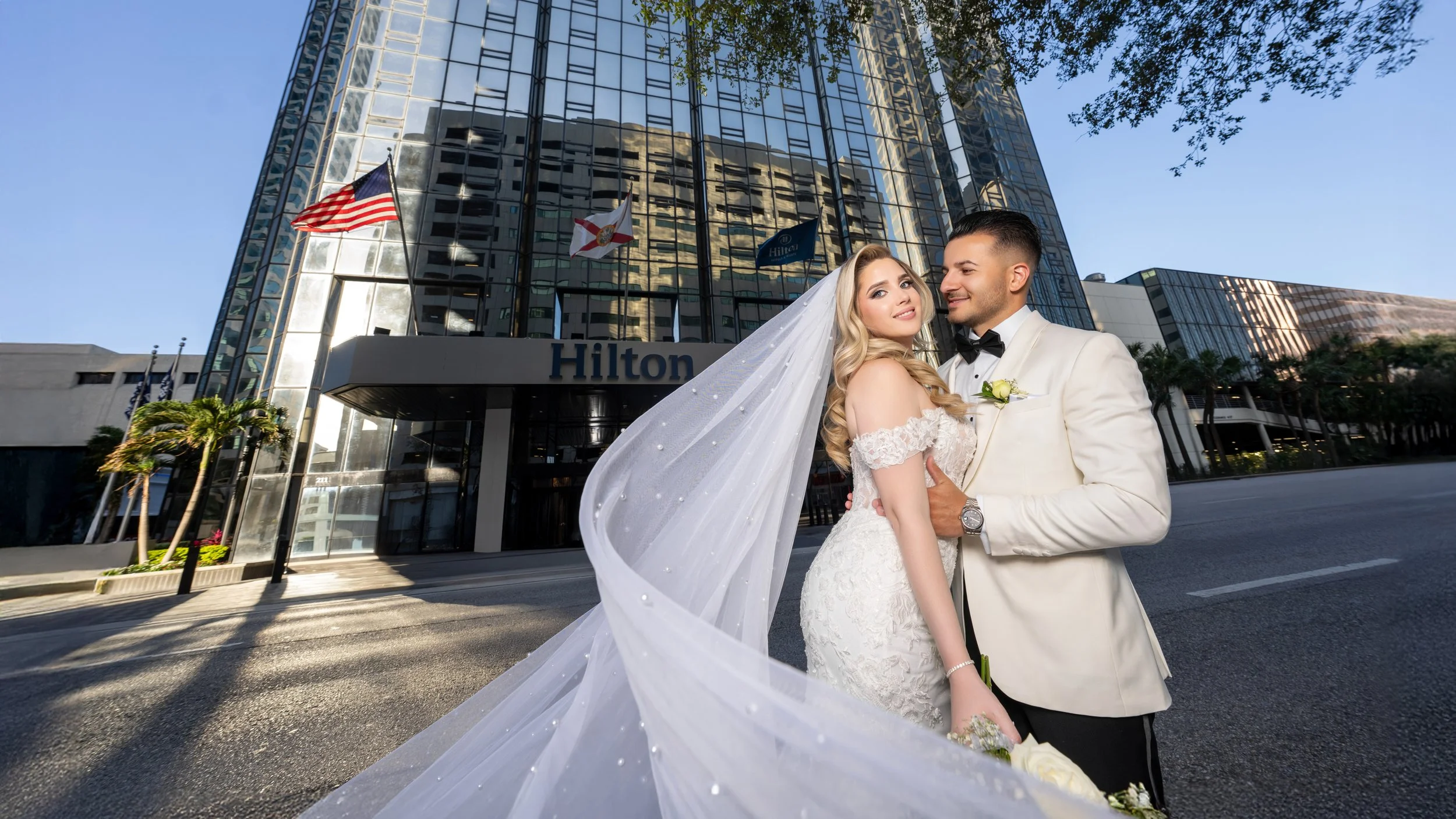 Modern newlyweds posing with giant LOVE marquee letters at HILTON TAMPA DOWNTOWN; creative wedding reception decor and photography by Star Visual Art, Tampa.