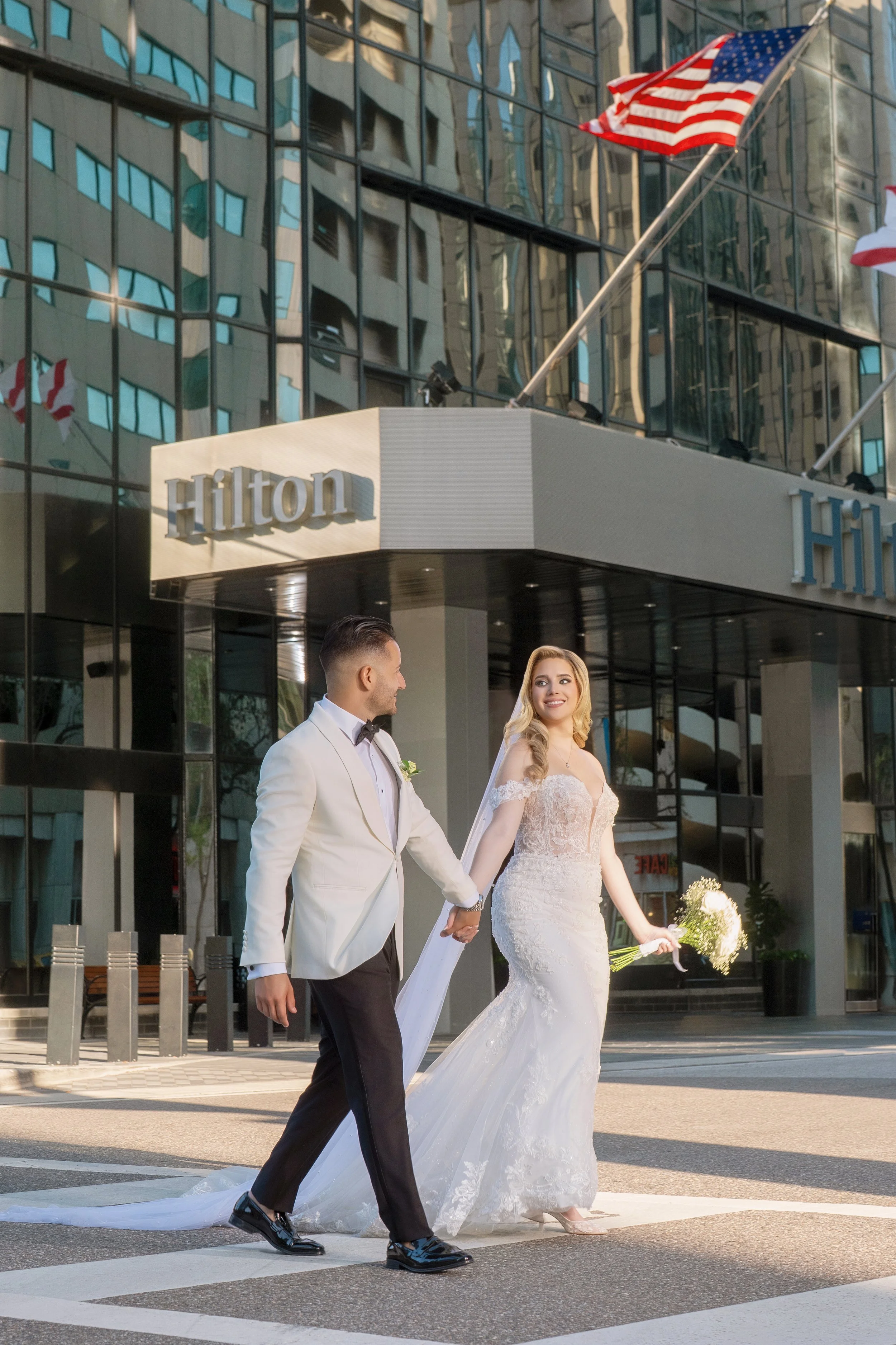 Newlyweds posing in front of the iconic HILTON TAMPA DOWNTOWN entrance; upscale city wedding photography by Star Visual Art, Tampa.