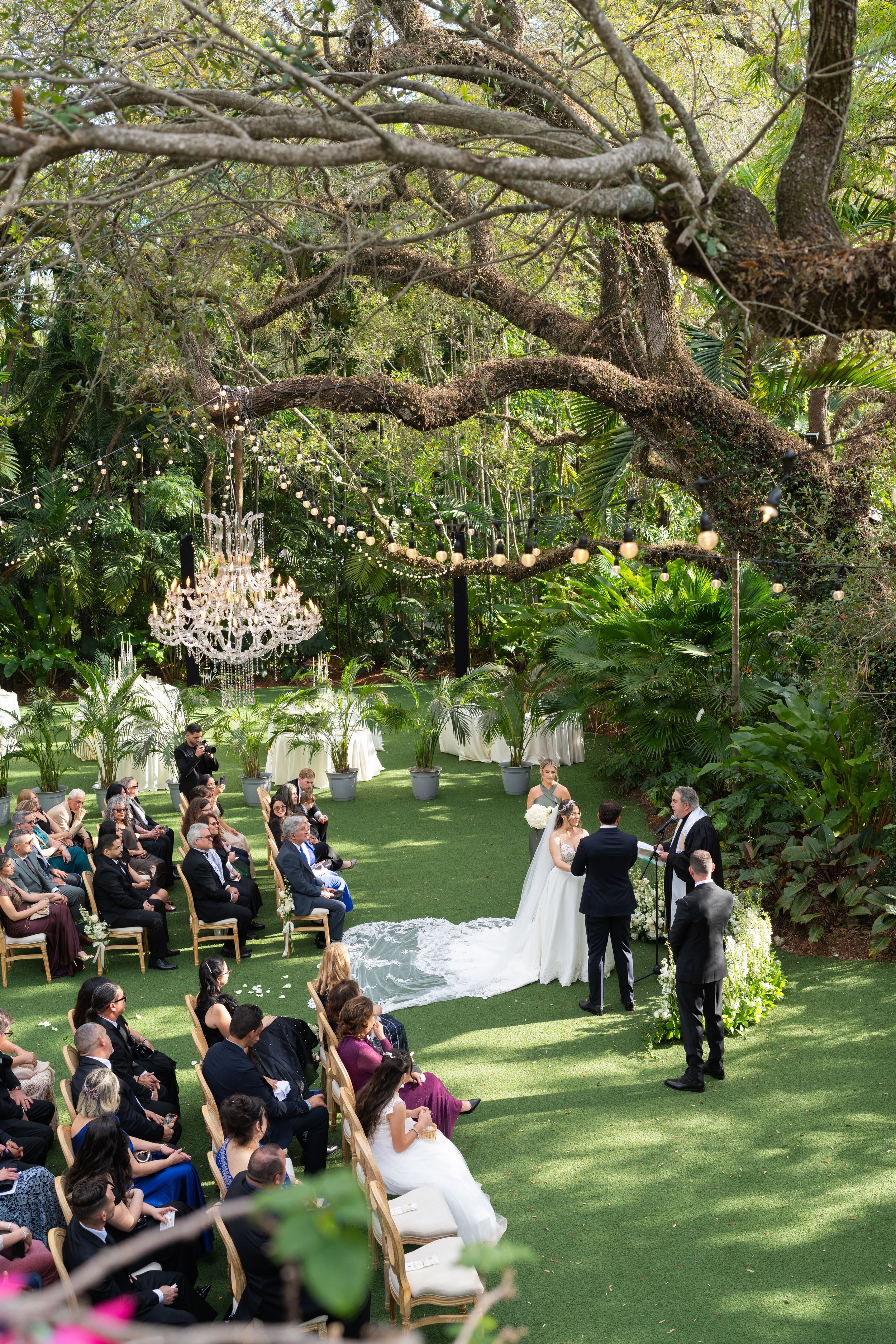 Aisle view of an outdoor wedding ceremony under the majestic Banyan tree at Villa Woodbine; captured by Star Visual Art, Miami wedding photographer.