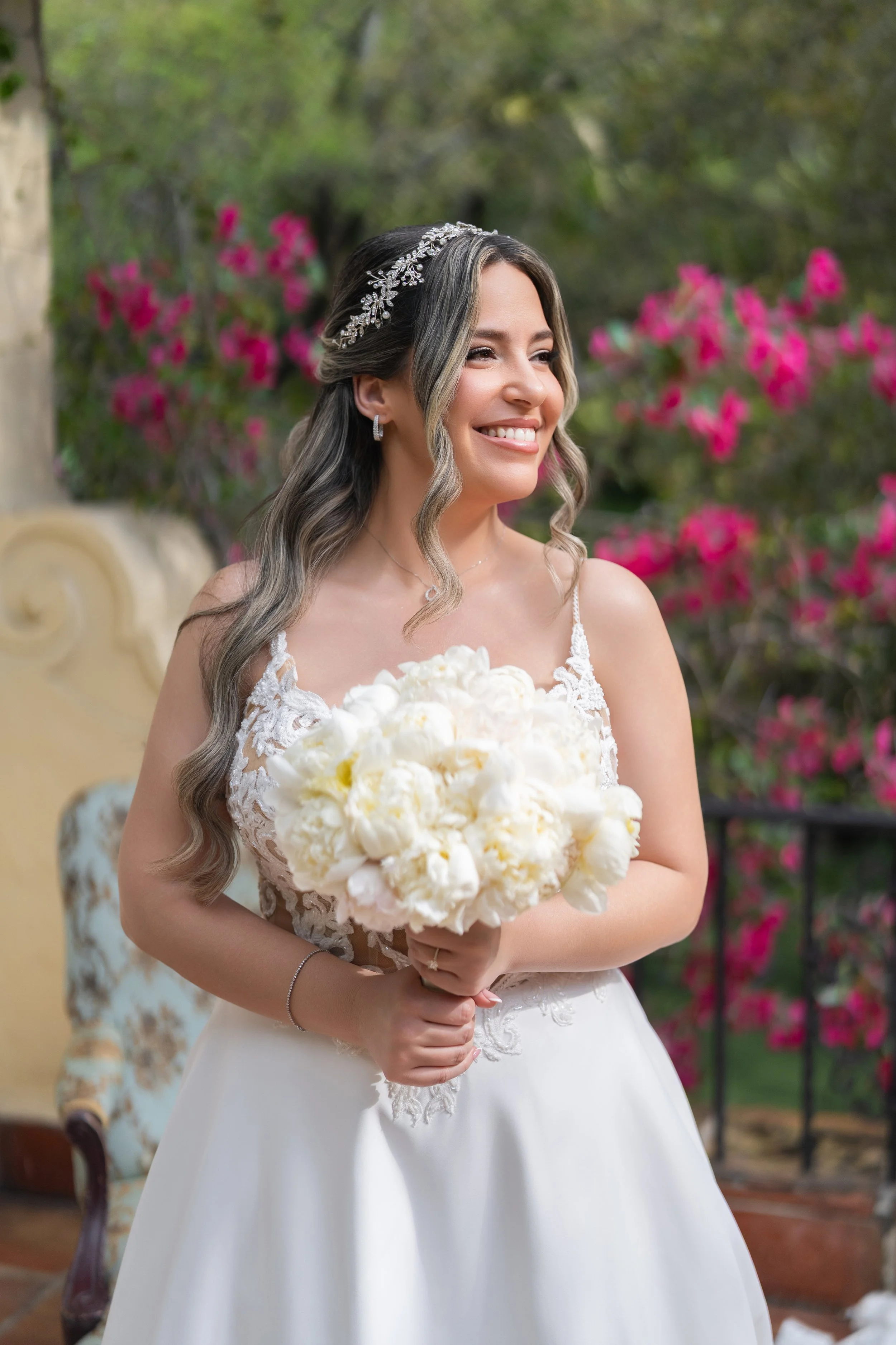 Radiant bride holding a white floral bouquet with pink bougainvillea background; fine art wedding photography by Star Visual Art, Miami.