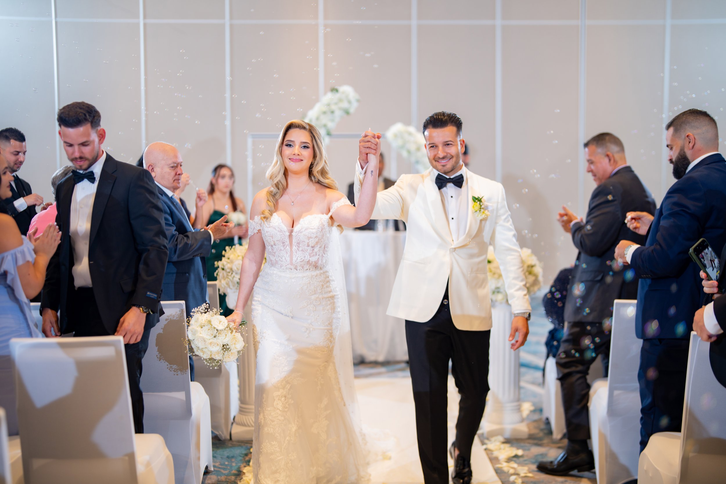 Joyful wedding recessional of the newlyweds at HILTON TAMPA DOWNTOWN; professional ceremony exit photography by Star Visual Art, Tampa.