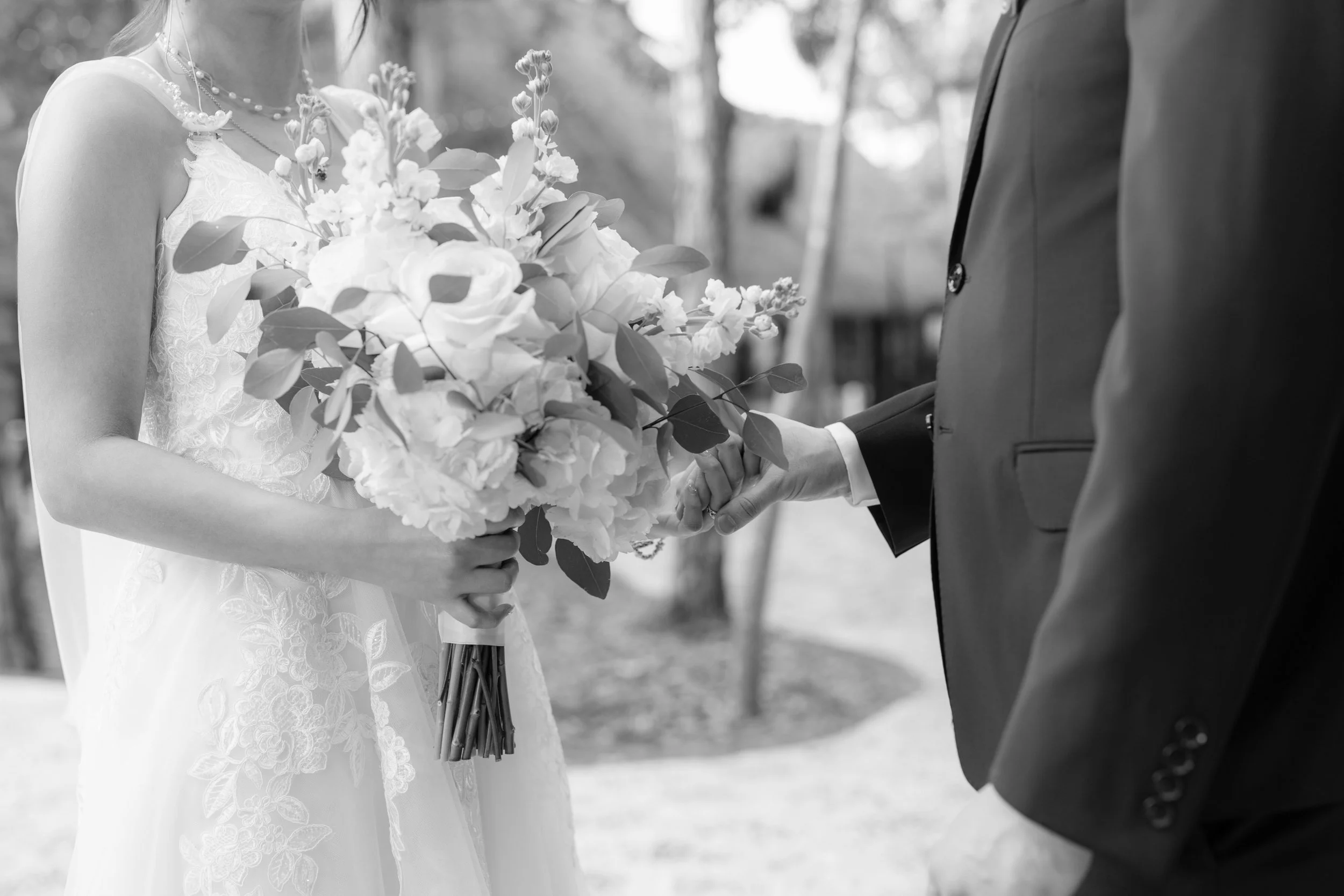 A bride and groom holding hands during their wedding ceremony, with the bride holding a bouquet of flowers.