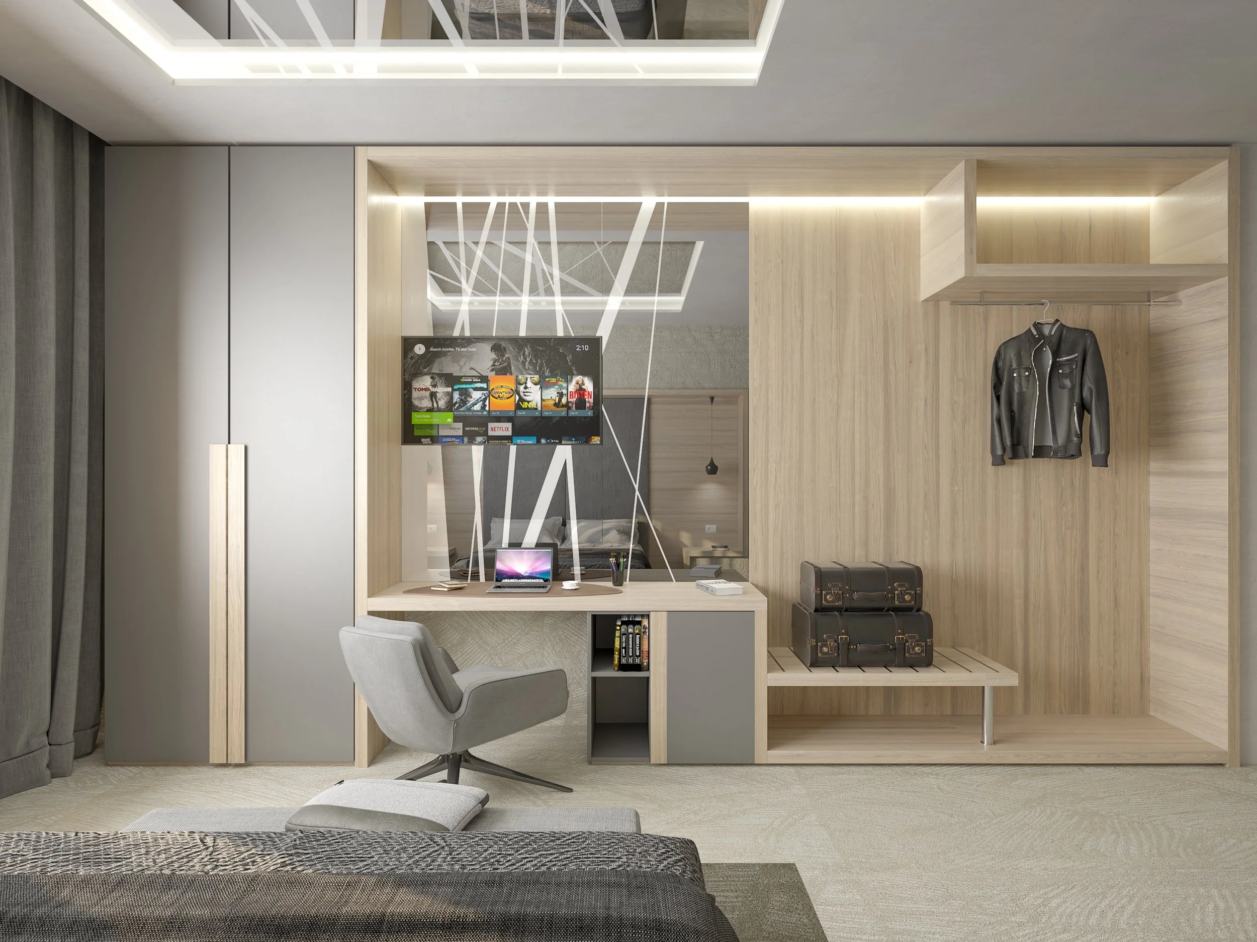 Vista di un angolo della camera con armadio in legno chiaro, scrivania con un monitor e una sedia grigia, televisore sullo sfondo e un letto parzialmente visibile in primo piano.