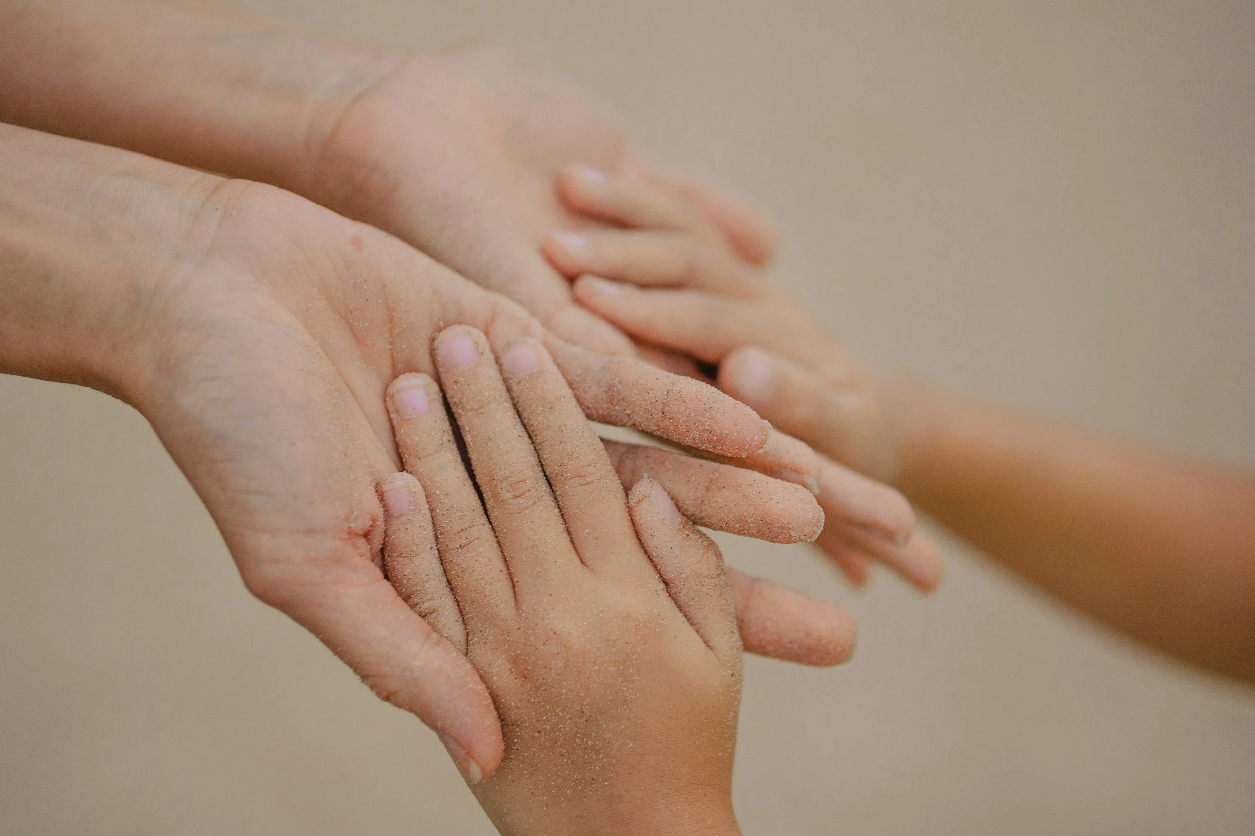 Multiple hands with sandy or dusty skin pressed together in a gesture of unity or teamwork.