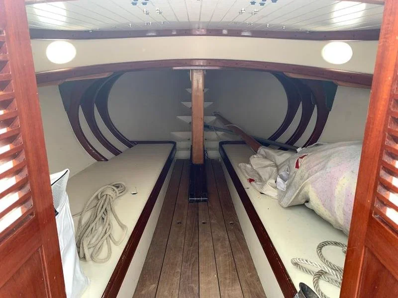 Interior of a boat with two sleeping berths on either side, a wooden floor, and a central support.