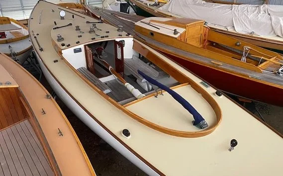 A small boat with an outboard engine, shown without a motor, parked among other smaller boats.
