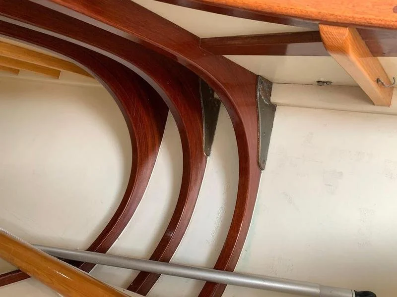 Close-up view of wooden and metal furniture or structural components, including curved wooden beams and metal support brackets attached to a white wall.