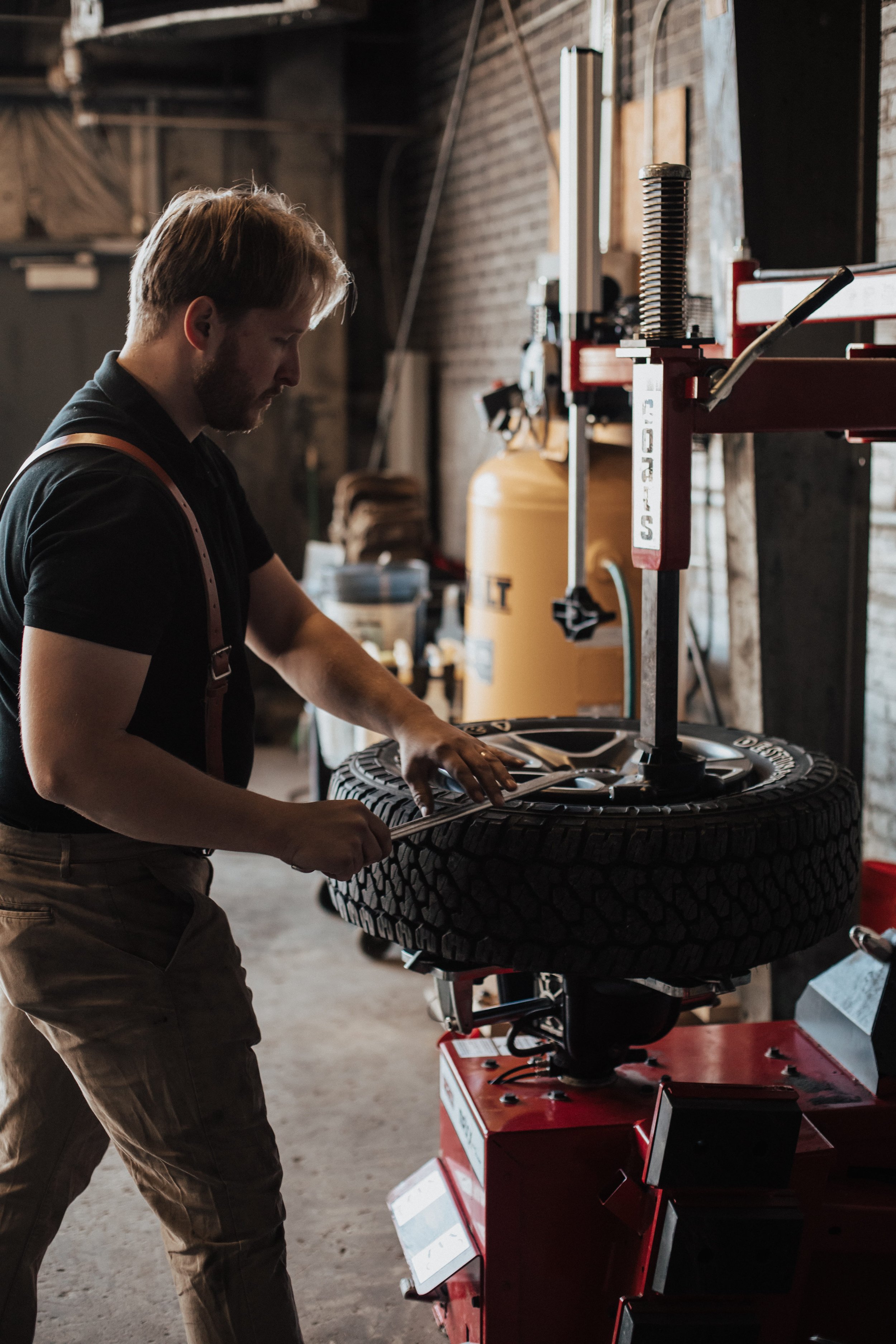 A man working on a car tire with a tire mounting machine in a garage or workshop.