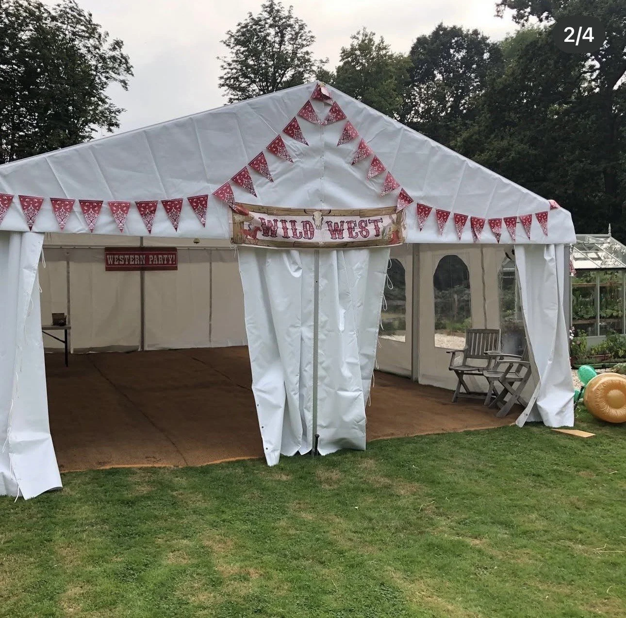 White event tent decorated with red bunting, labeled 'Wild West', with a 'Western Party' sign inside, set up on grass with chairs and balloons outside.