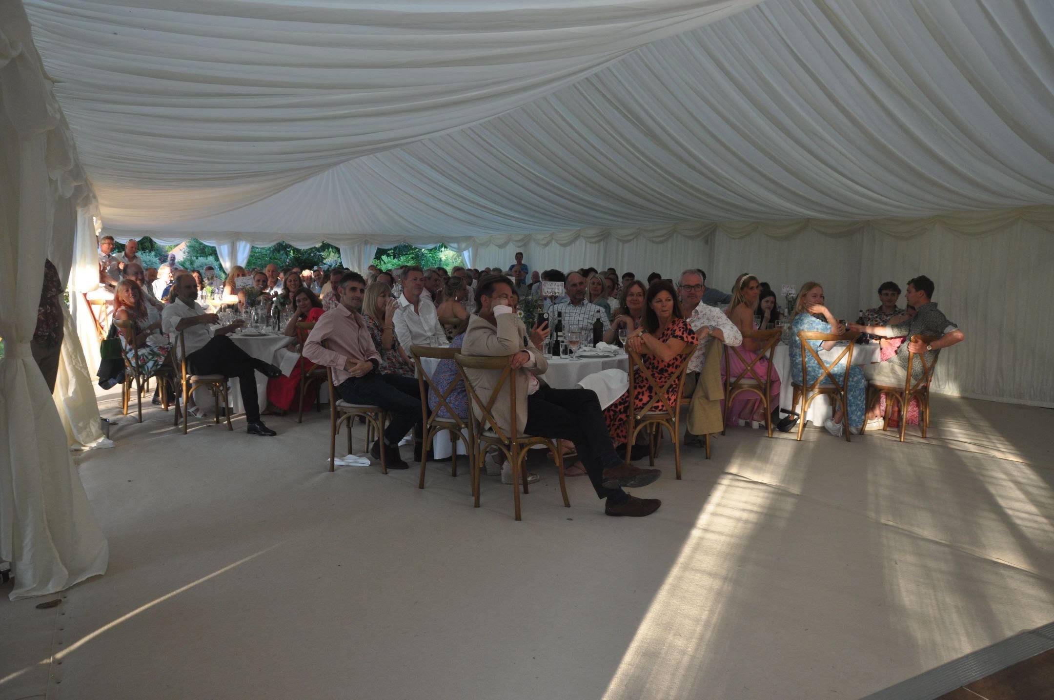 Guests seated at tables during a wedding reception inside a large, white marquee in mortimer west berkshire uk