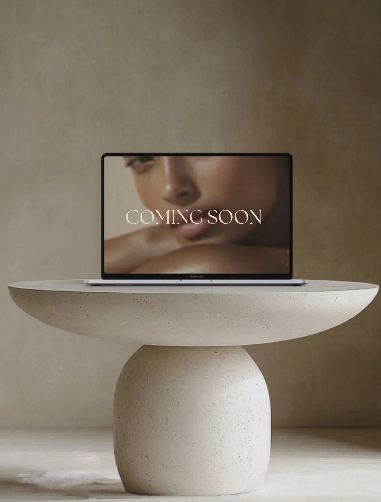 Laptop displaying a modern website on a stone table in a neutral setting, representing website design and development