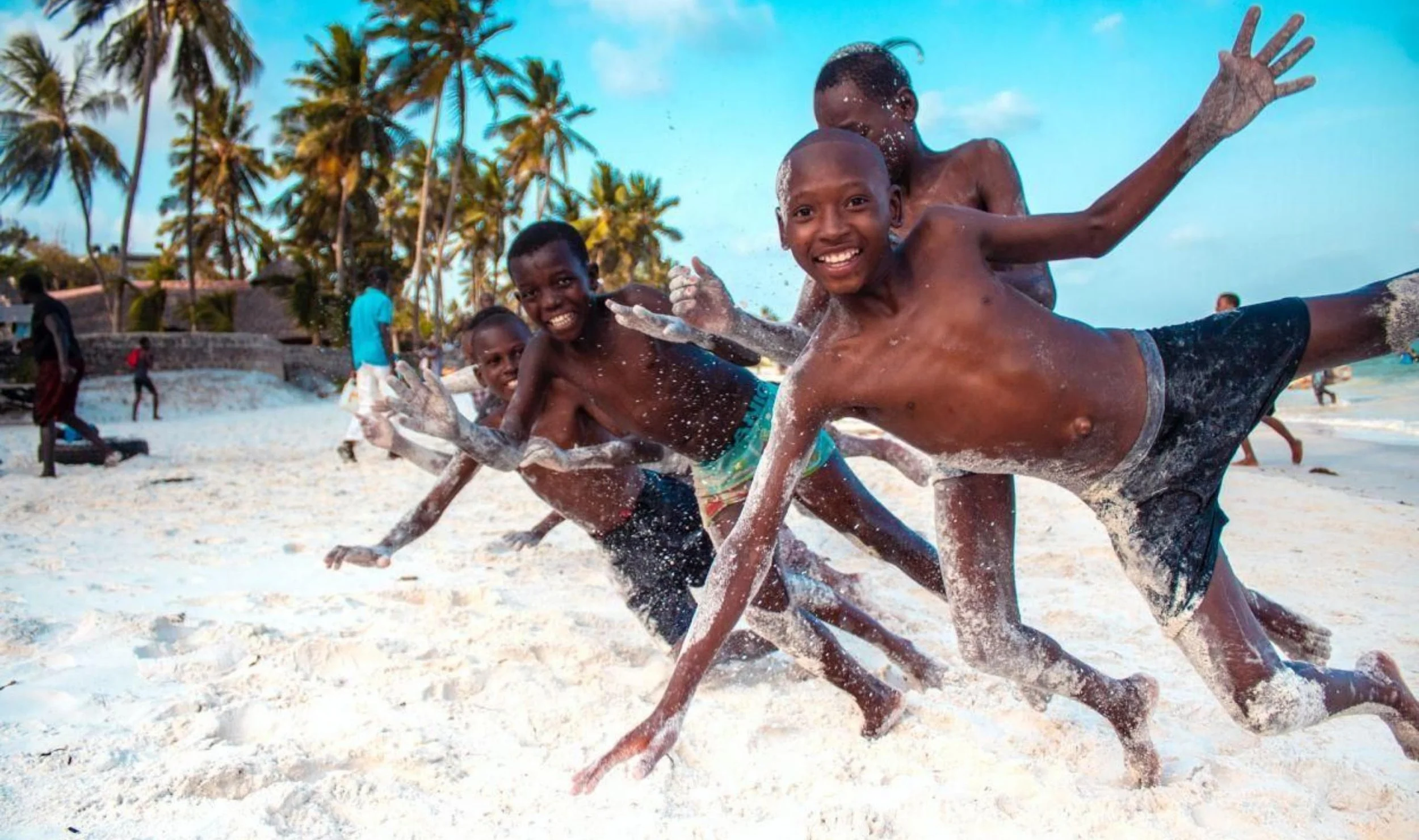 Young boys smiling and playing on a beach in Zanzibar.